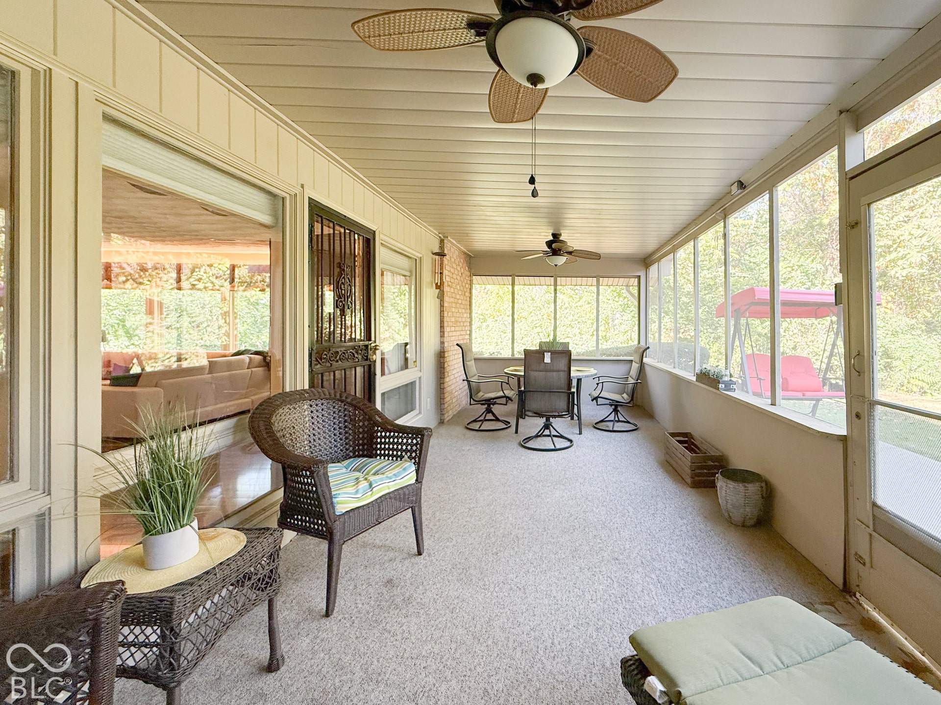 4225 Westbourne Drive, Indianapolis, IN 46205 Enclosed sunroom featuring expansive screened windows, light-toned wall paneling, dual ceiling fans, and a brick accent wall