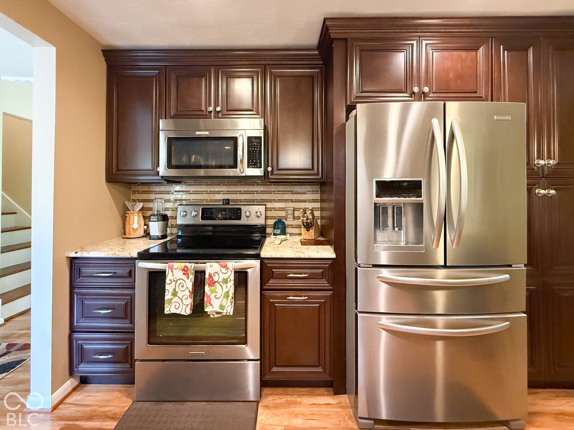 4225 Westbourne Drive, Indianapolis, IN 46205 Dark-toned cabinetry featuring crown molding, stone-finish countertops, stainless steel appliances, and horizontal tile backsplash