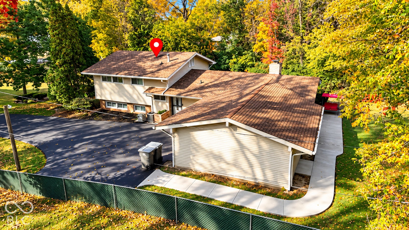 4225 Westbourne Drive, Indianapolis, IN 46205 Split-level residence featuring light-colored horizontal siding, a pitched asphalt shingle roof, an expansive asphalt driveway, and a concrete walkway