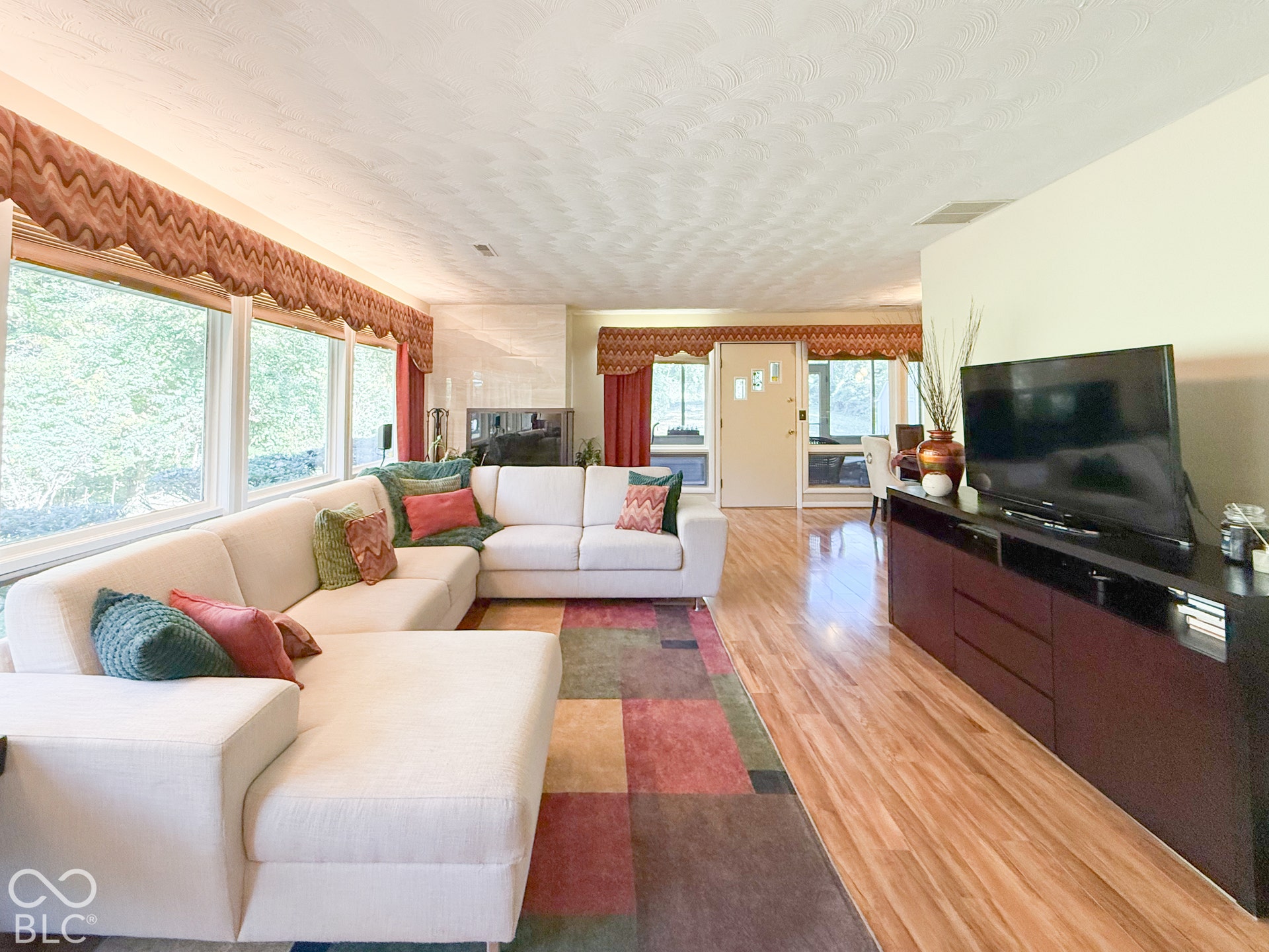 4225 Westbourne Drive, Indianapolis, IN 46205 Living area featuring expansive windows, wood-finish flooring, and a fireplace with a light-toned brick surround