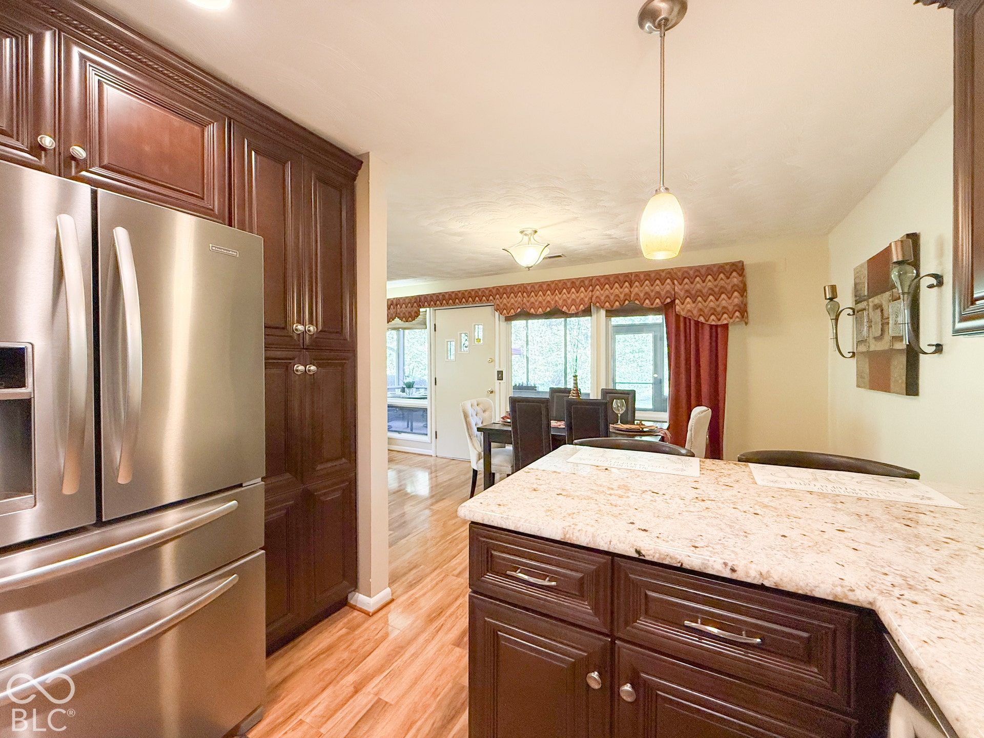 4225 Westbourne Drive, Indianapolis, IN 46205 Kitchen featuring custom dark wood cabinetry, stainless steel refrigerator, stone countertops, pendant lighting, and wood-finish flooring