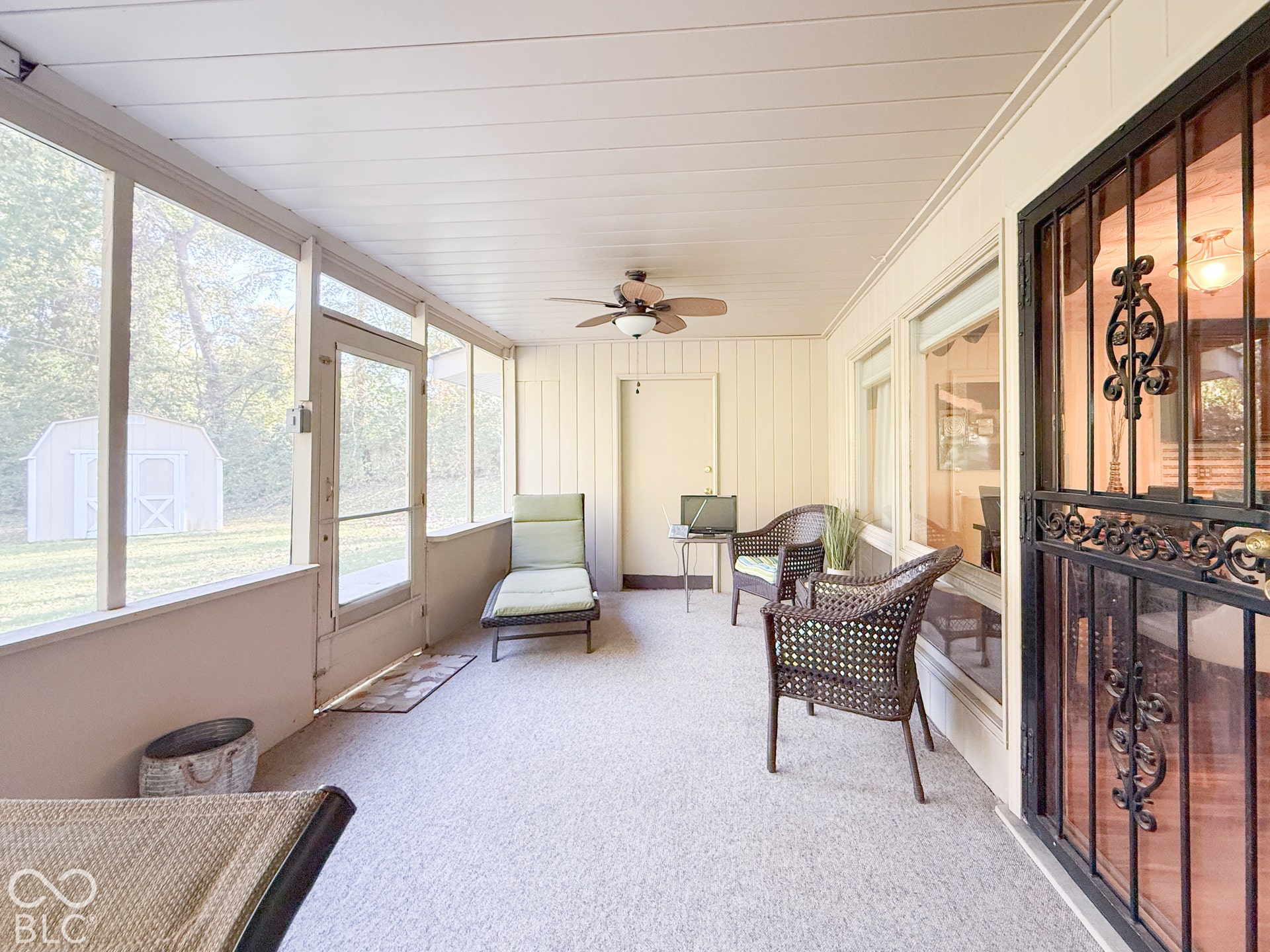 4225 Westbourne Drive, Indianapolis, IN 46205 Screened-in porch featuring a beadboard ceiling, ceiling fan with integrated lighting, full-height window panels, and a metal security screen door with decorative scrollwork