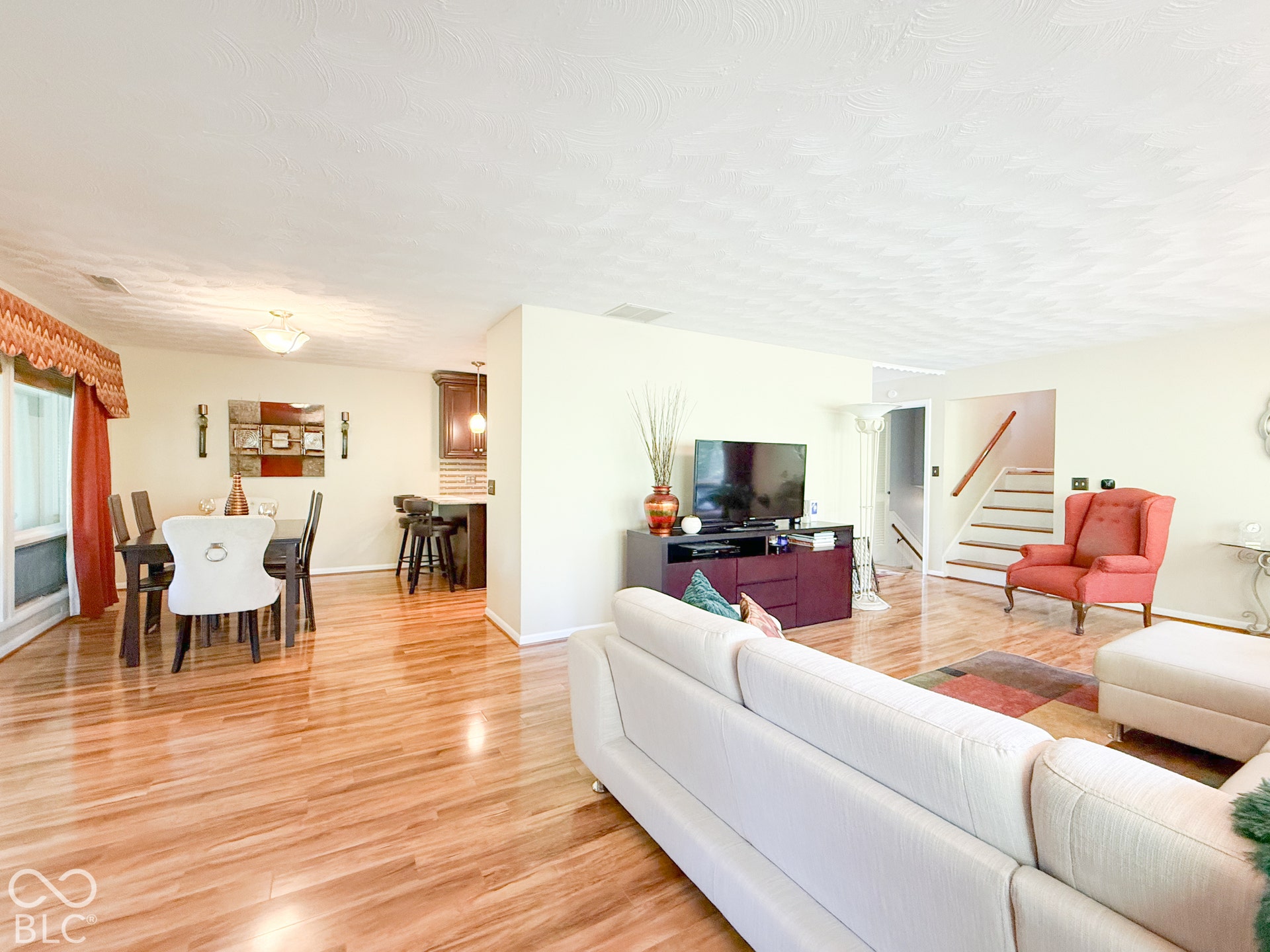 4225 Westbourne Drive, Indianapolis, IN 46205 Open-concept interior featuring light-toned wood-finish flooring, textured ceilings, recessed lighting, and a staircase with a wooden handrail