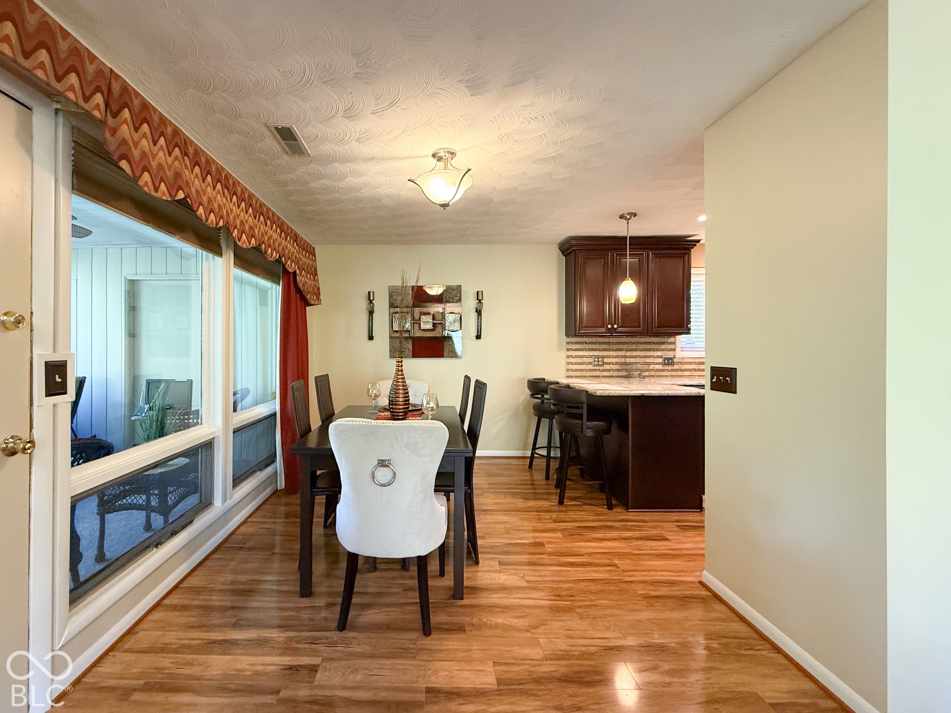 4225 Westbourne Drive, Indianapolis, IN 46205 Open-concept area featuring wood-finish flooring, dark wood-tone cabinetry, stone-surface breakfast bar, and large windows with integrated hardware