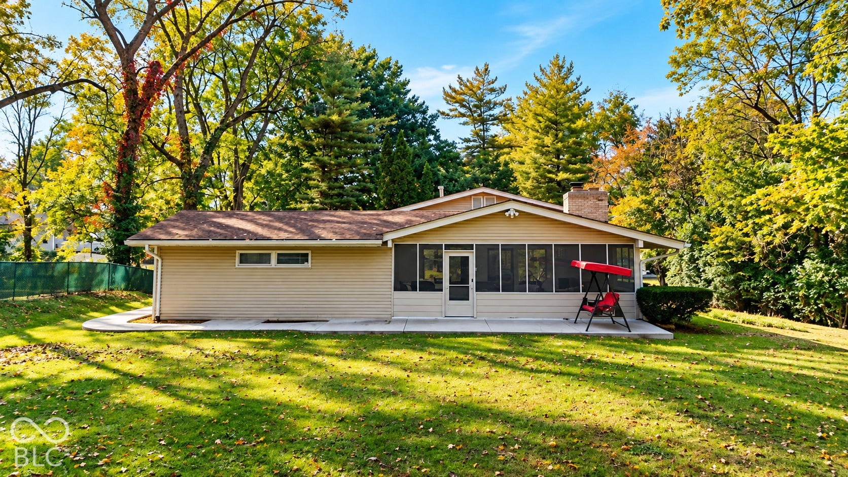 4225 Westbourne Drive, Indianapolis, IN 46205 Rear elevation featuring a screened porch, exterior chimney, concrete patio, and mature trees on a level lot
