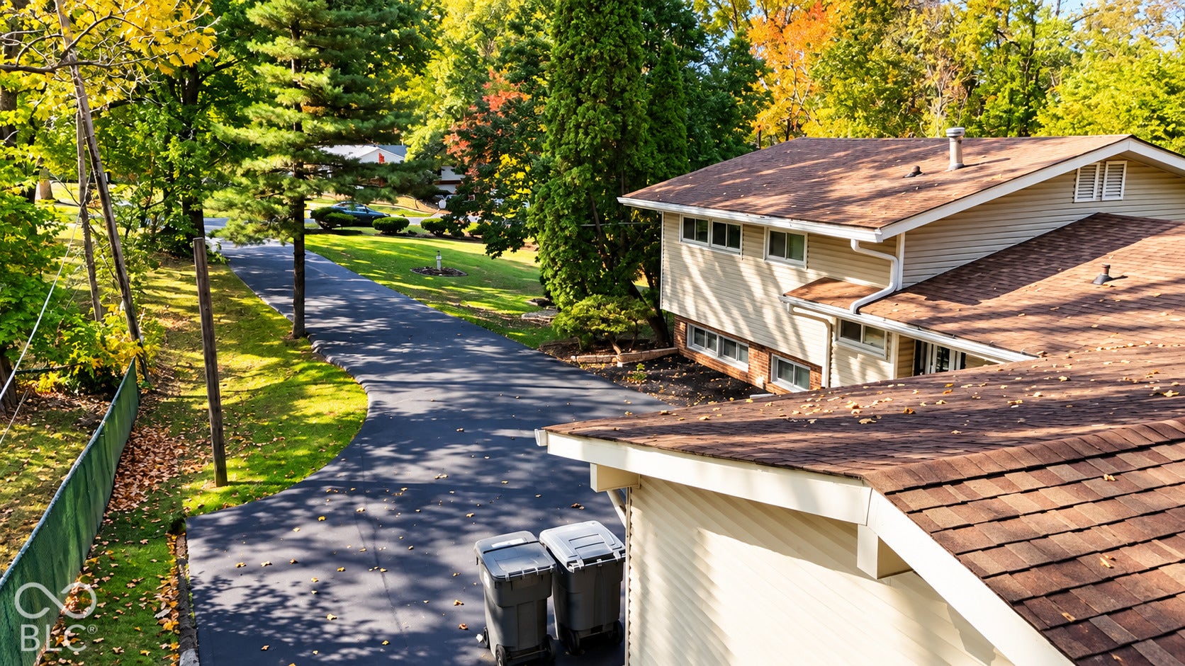4225 Westbourne Drive, Indianapolis, IN 46205 Exterior featuring a multi-level structure with light-colored siding, a brown shingle roof, and a paved asphalt driveway