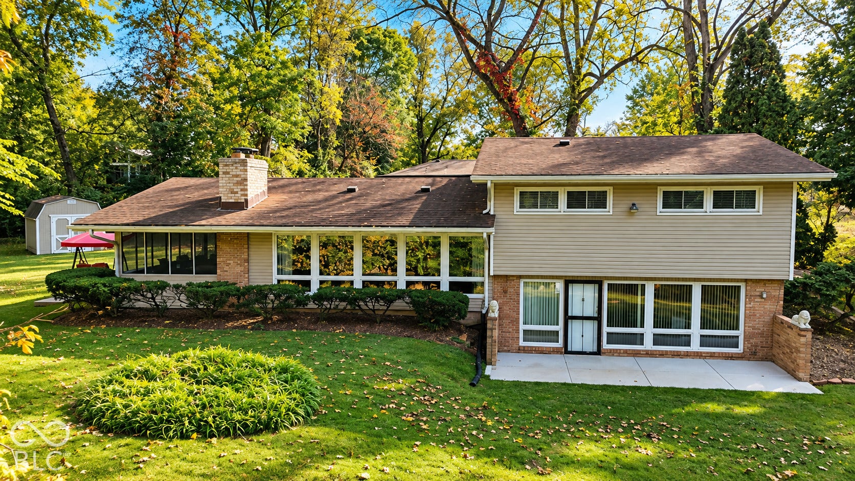 4225 Westbourne Drive, Indianapolis, IN 46205 Multi-level exterior featuring horizontal siding, brick masonry detailing, an expansive wall of windows, an attached masonry chimney, and a concrete patio