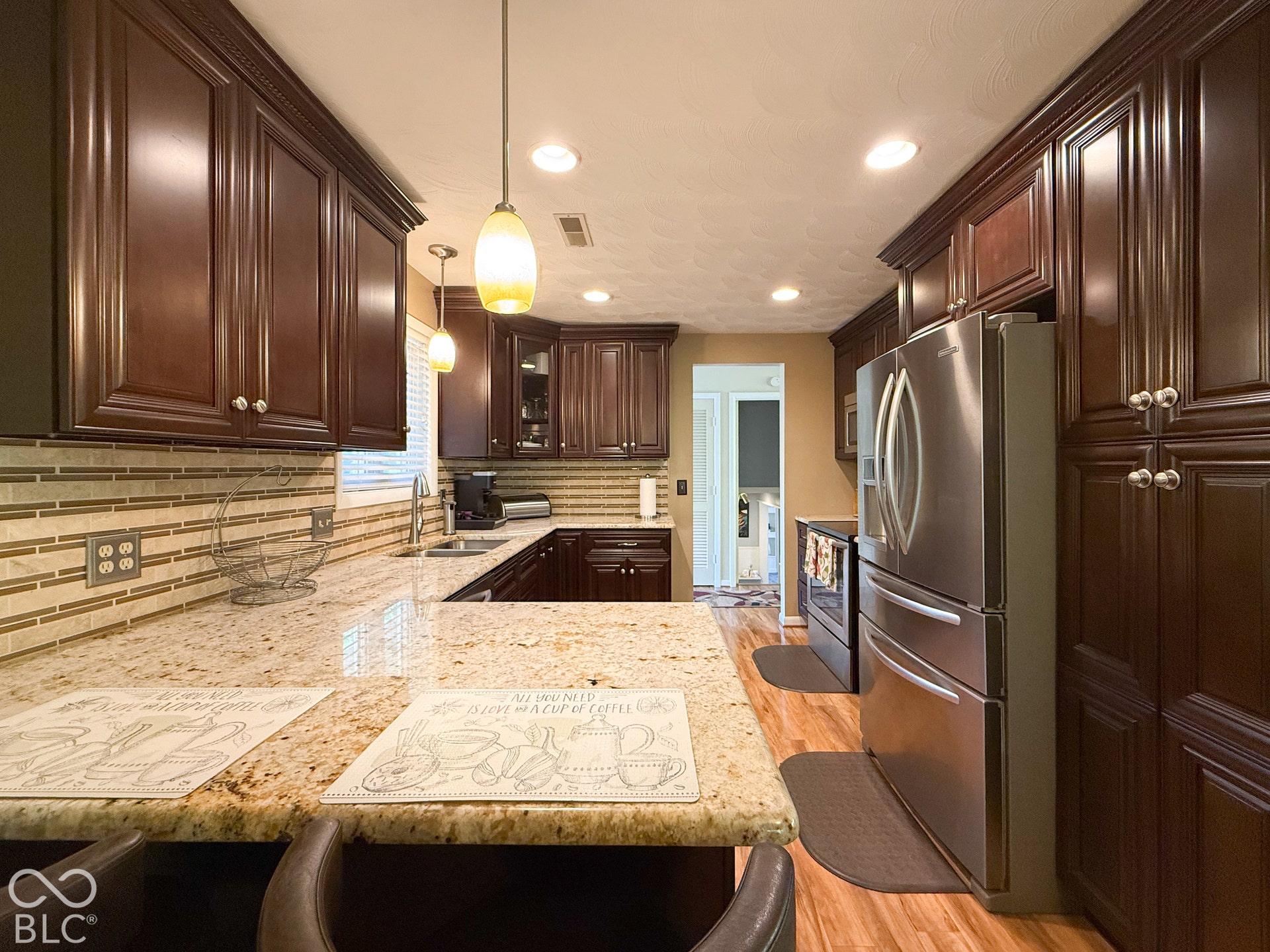 4225 Westbourne Drive, Indianapolis, IN 46205 Kitchen featuring dark wood cabinetry, stone countertops, stainless steel appliances, multi-toned tile backsplash, and recessed and pendant lighting