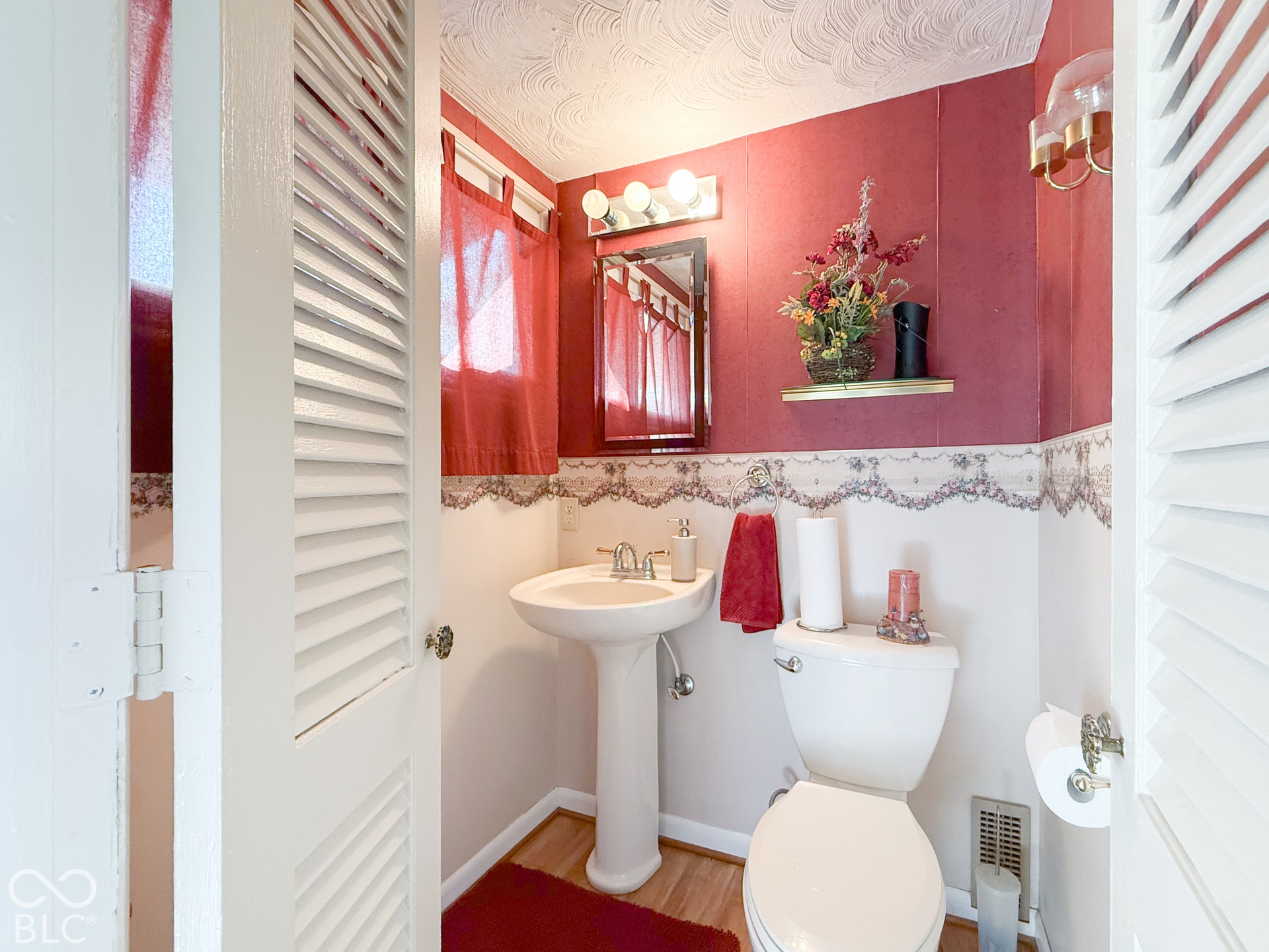 4225 Westbourne Drive, Indianapolis, IN 46205 Pedestal sink with polished chrome hardware, wall-mounted medicine cabinet, three-bulb vanity light fixture, and wood-finish flooring