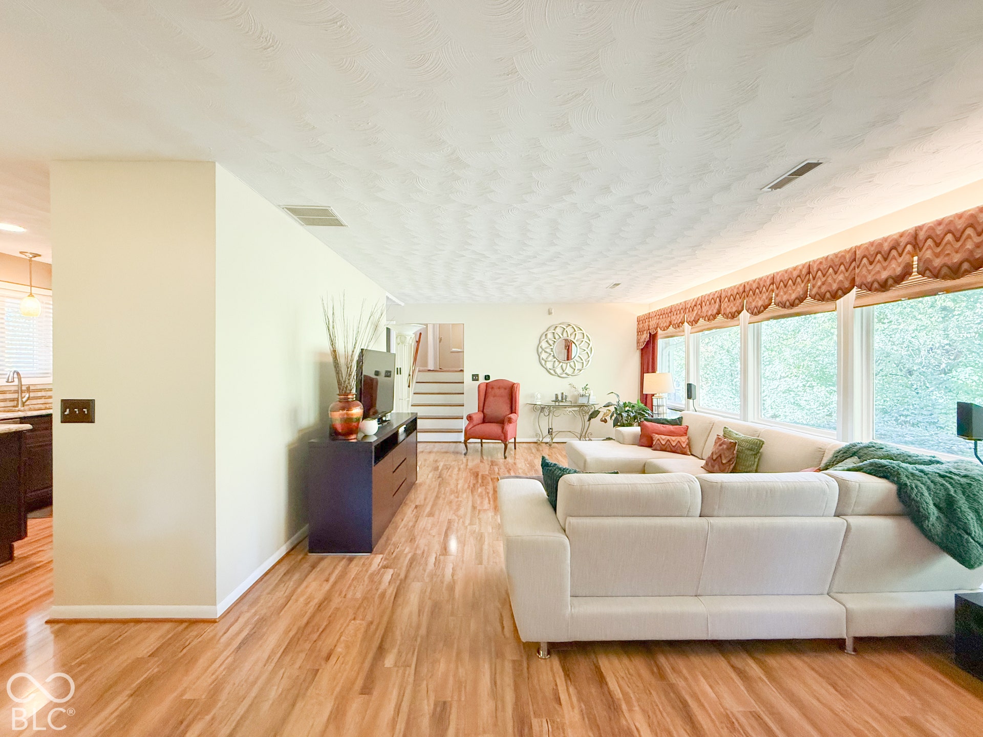 4225 Westbourne Drive, Indianapolis, IN 46205 Living area featuring wood-finish flooring, a wall-to-wall window arrangement, and a textured ceiling