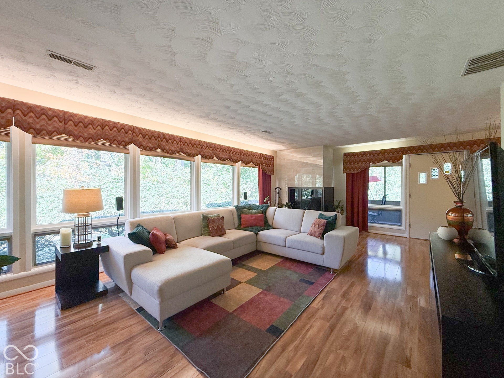 4225 Westbourne Drive, Indianapolis, IN 46205 Expansive floor-to-ceiling windows, wood-finish flooring, textured ceiling, and a fireplace with a sleek surround