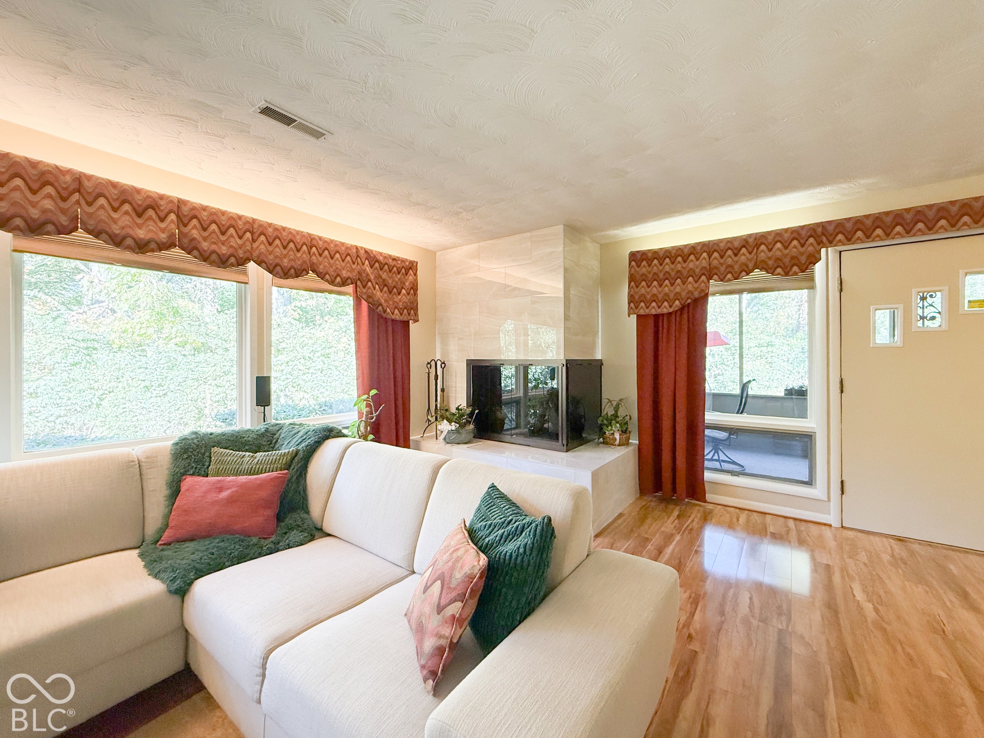 4225 Westbourne Drive, Indianapolis, IN 46205 Fireplace with stone-style surround and raised hearth, wood-finish flooring, and multiple large windows with natural lighting