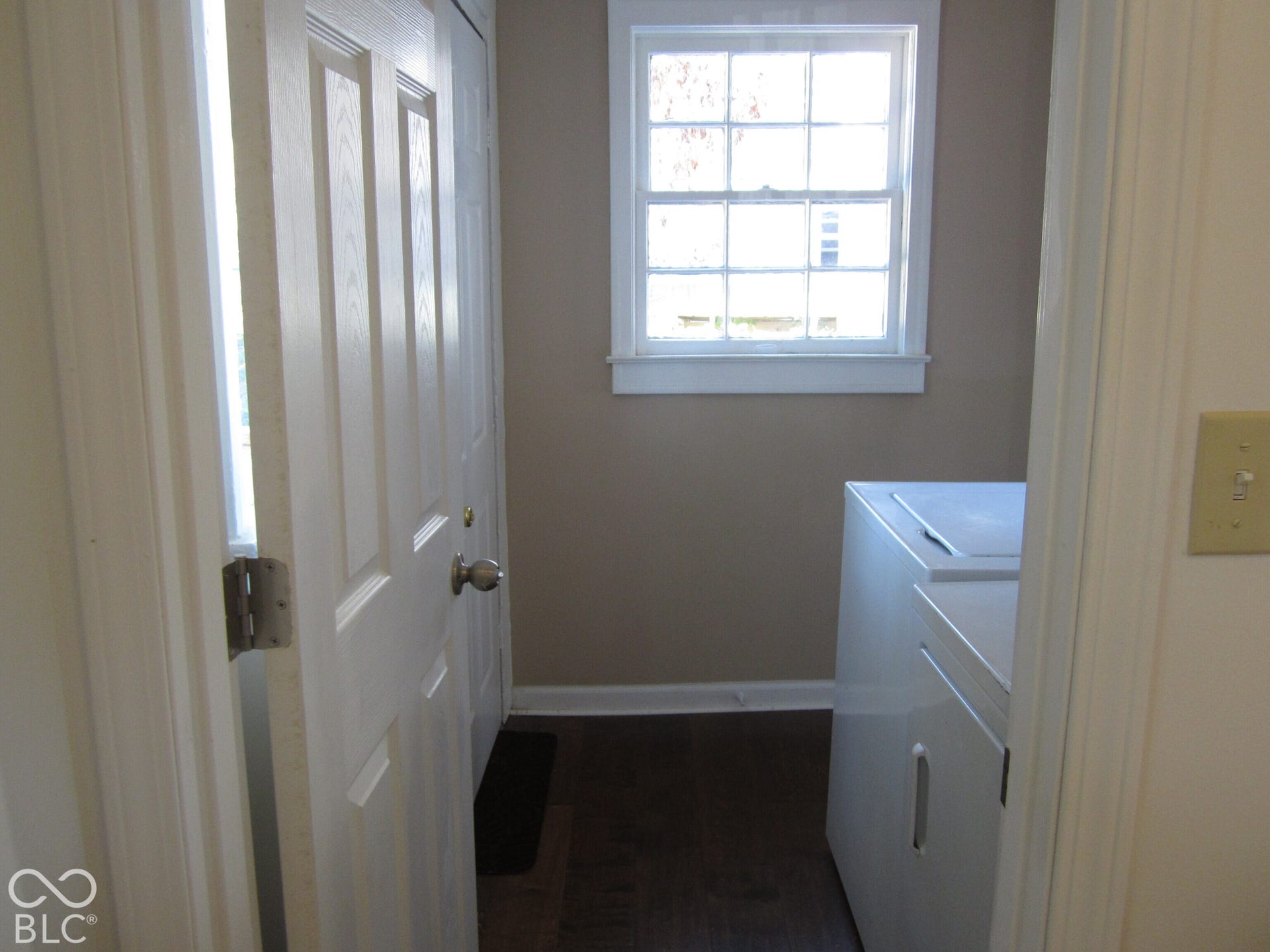 Multi-pane window with white trim, wood-finish flooring, and white panel doors
