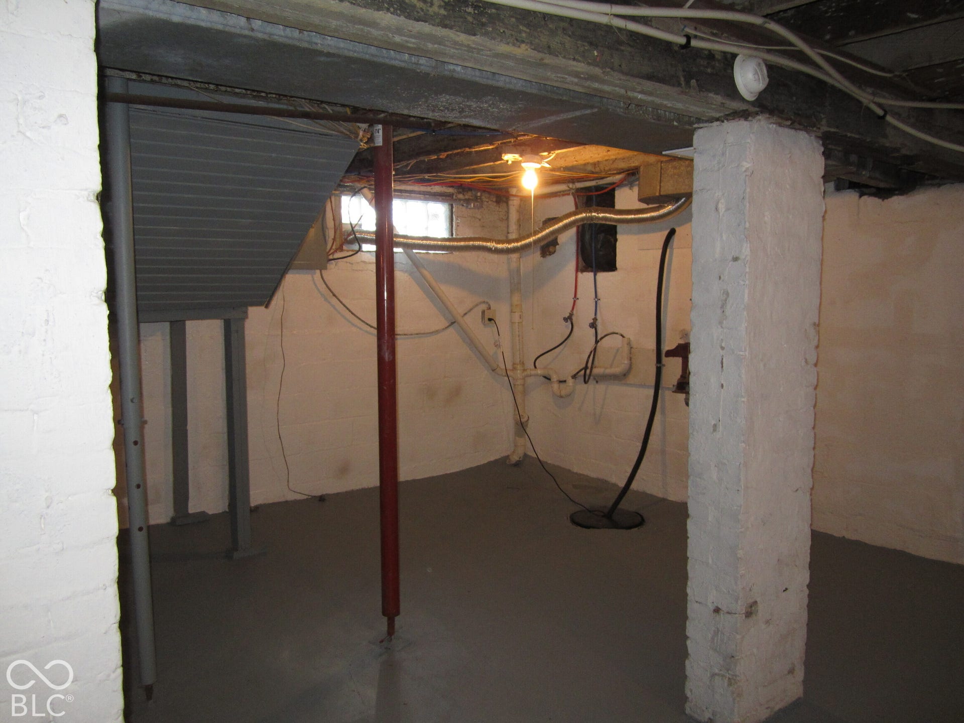 Unfinished lower level featuring painted masonry walls, a concrete floor, exposed ceiling joists, and structural steel support columns