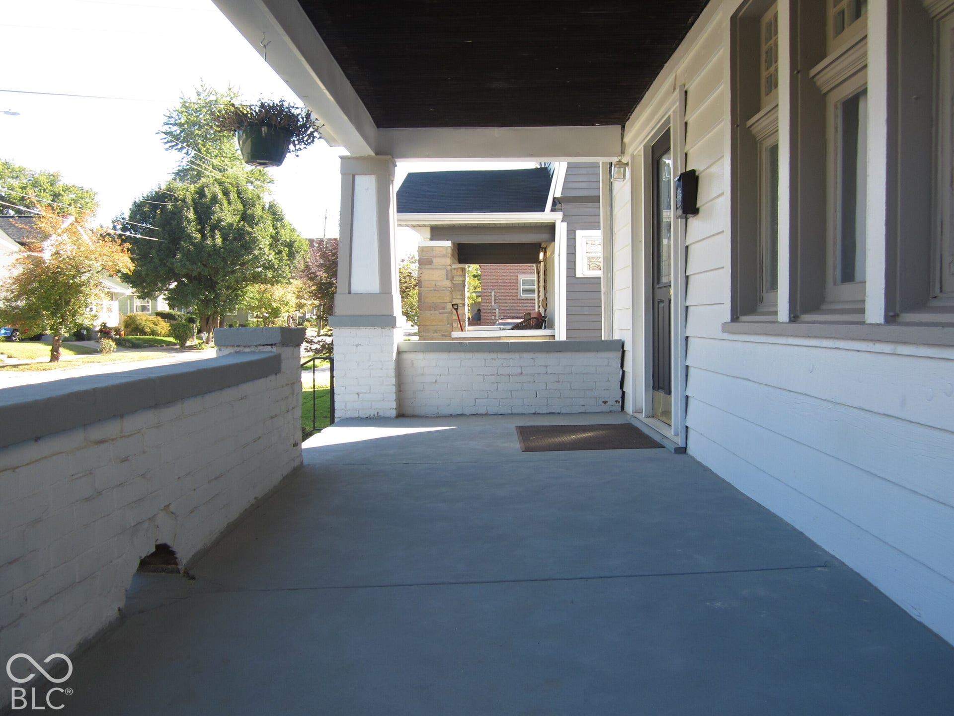 Covered porch featuring painted brick masonry, substantial structural pillars, horizontal lap siding, and multi-pane windows
