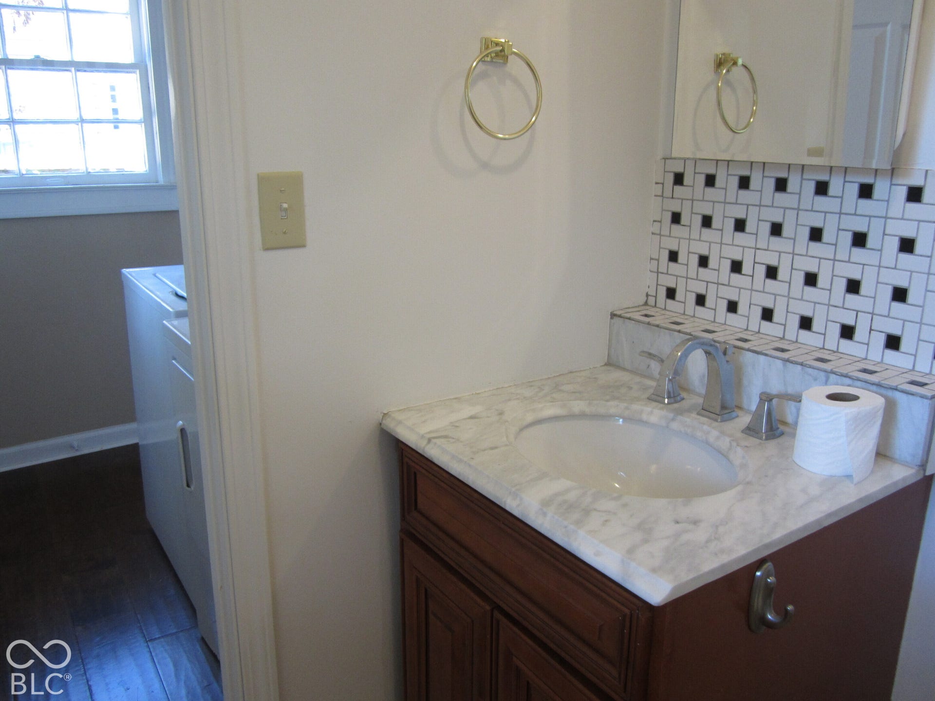 Vanity featuring a stone-top counter, undermount sink, metallic hardware, and a geometric-patterned tile backsplash