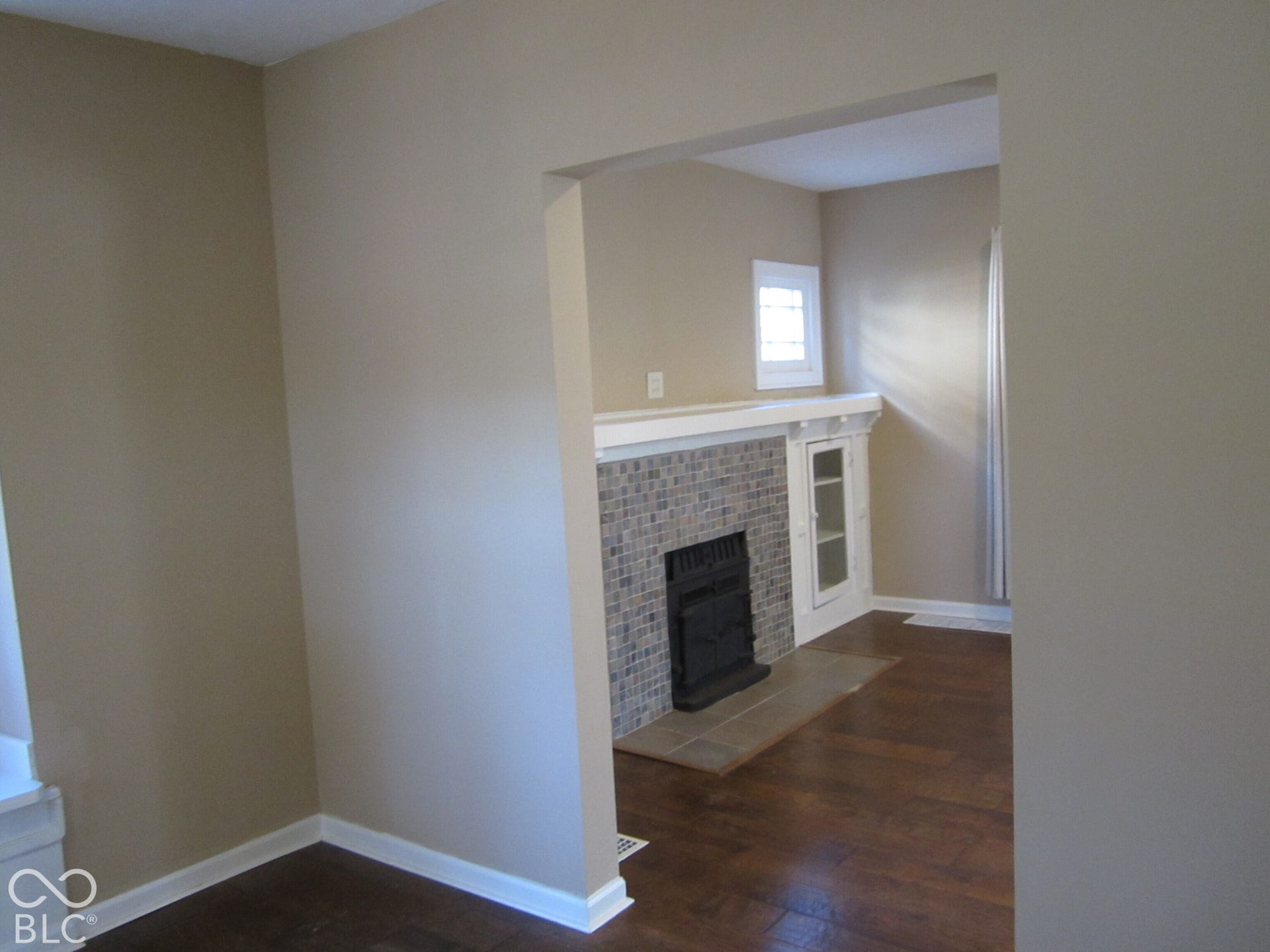 Fireplace featuring a mosaic tile surround, wood-finish flooring, and built-in glass-front cabinetry