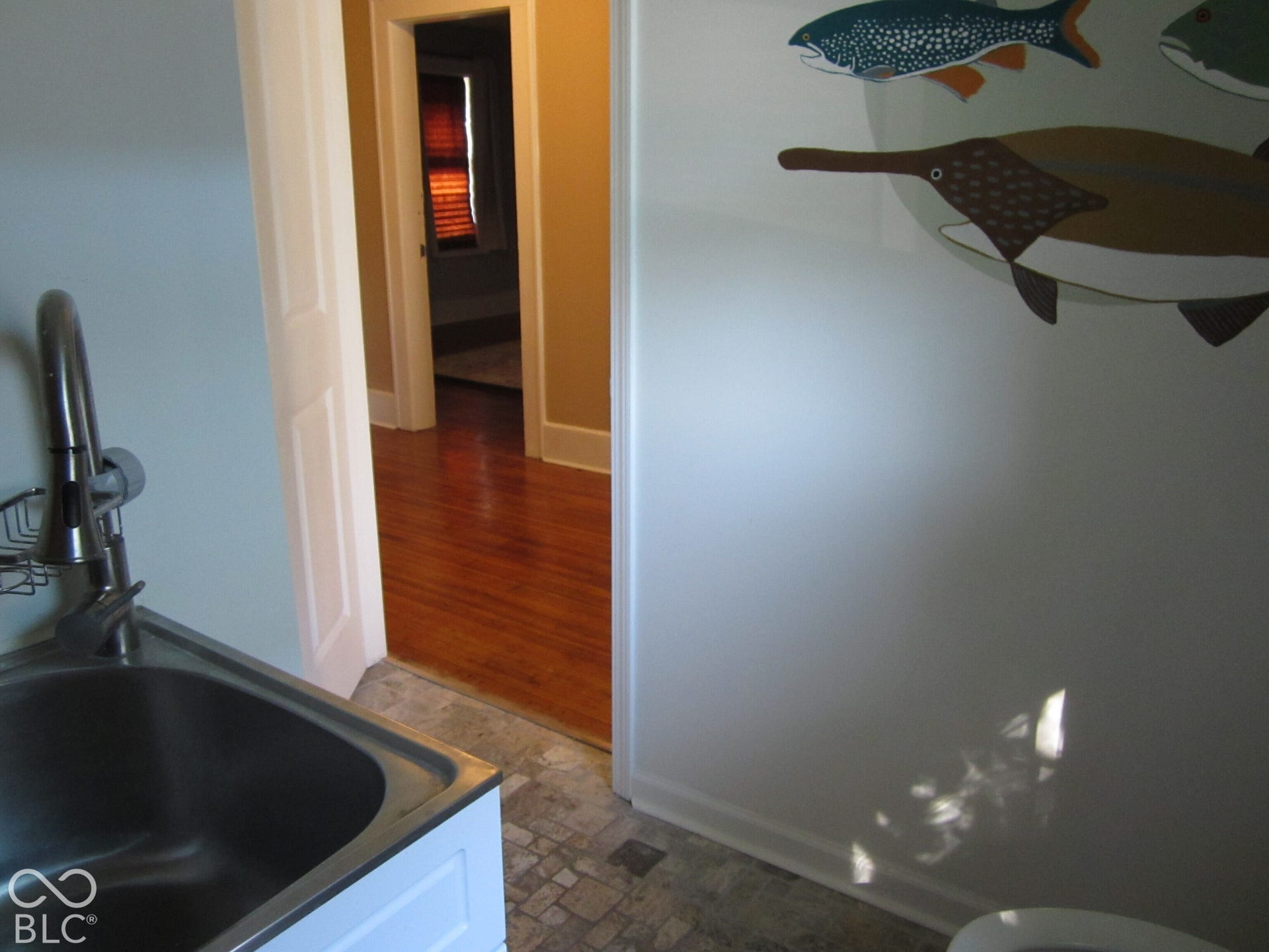 Stainless steel high-arc faucet, integrated basin, stone-patterned tile flooring, and polished wood-finish flooring
