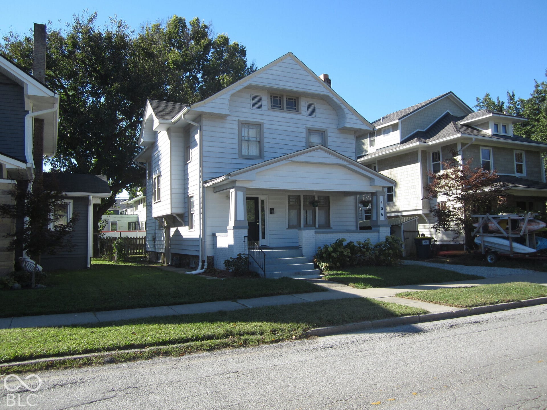 Two-story residence featuring horizontal lap siding, a covered front porch with tapered columns, gable roof lines, and a dedicated concrete walkway