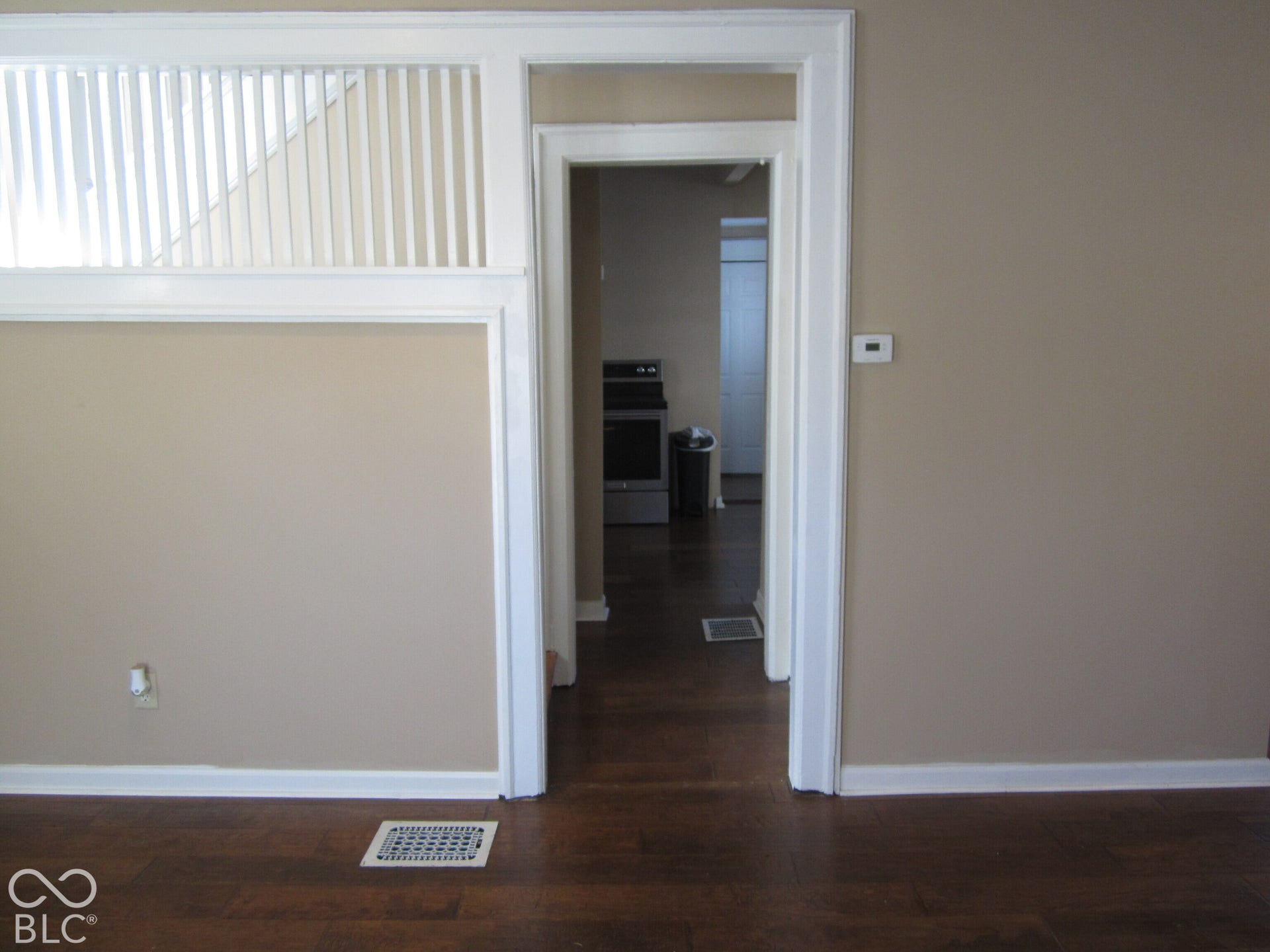 Interior featuring dark wood-finish flooring, white millwork trim, and a built-in wooden staircase screen with vertical balusters
