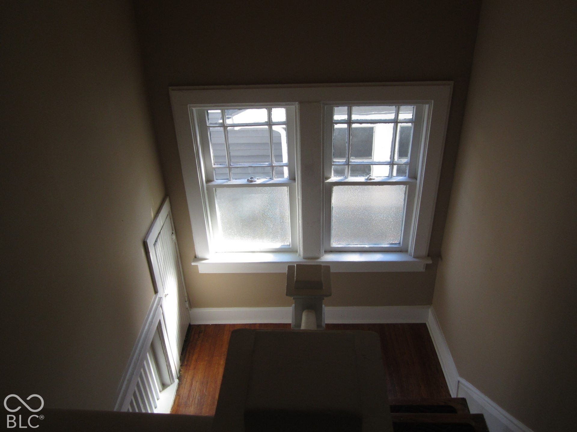 Double-hung windows featuring multi-pane upper sashes, integrated millwork, wood-finish flooring, and built-in wall cabinetry
