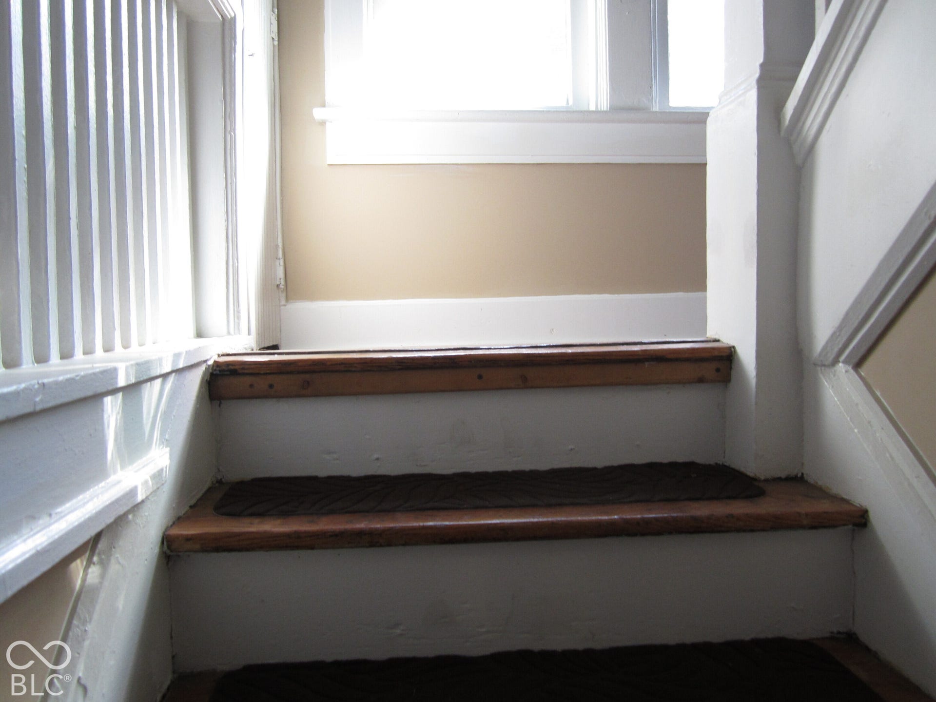 Staircase featuring natural wood-finish treads, painted risers, and white architectural trim