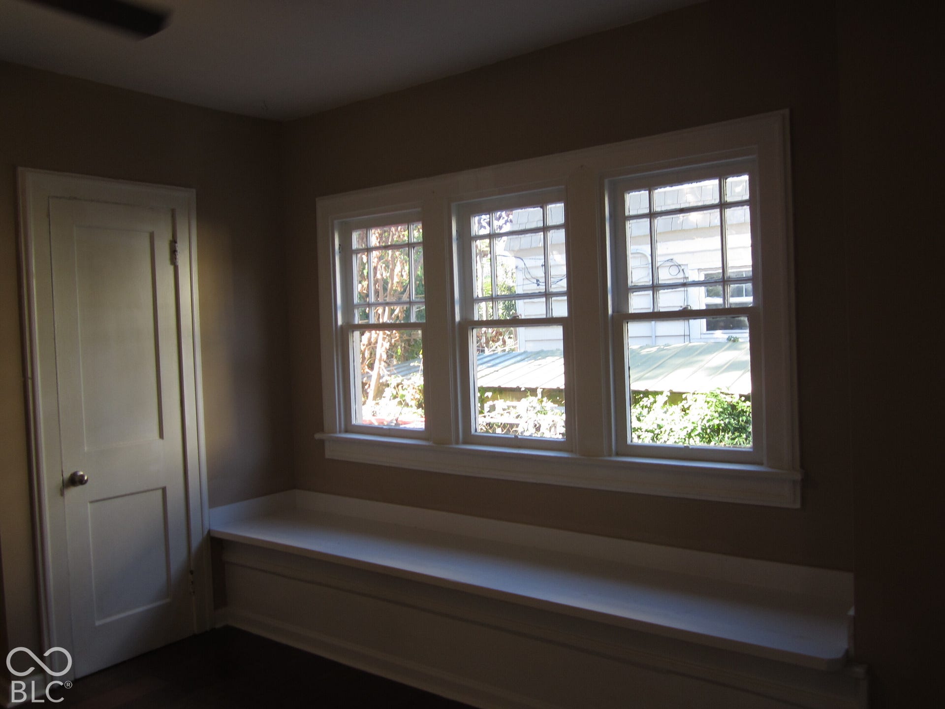 Built-in window seat featuring white millwork, paired with a triple-pane window unit and a single-panel interior door