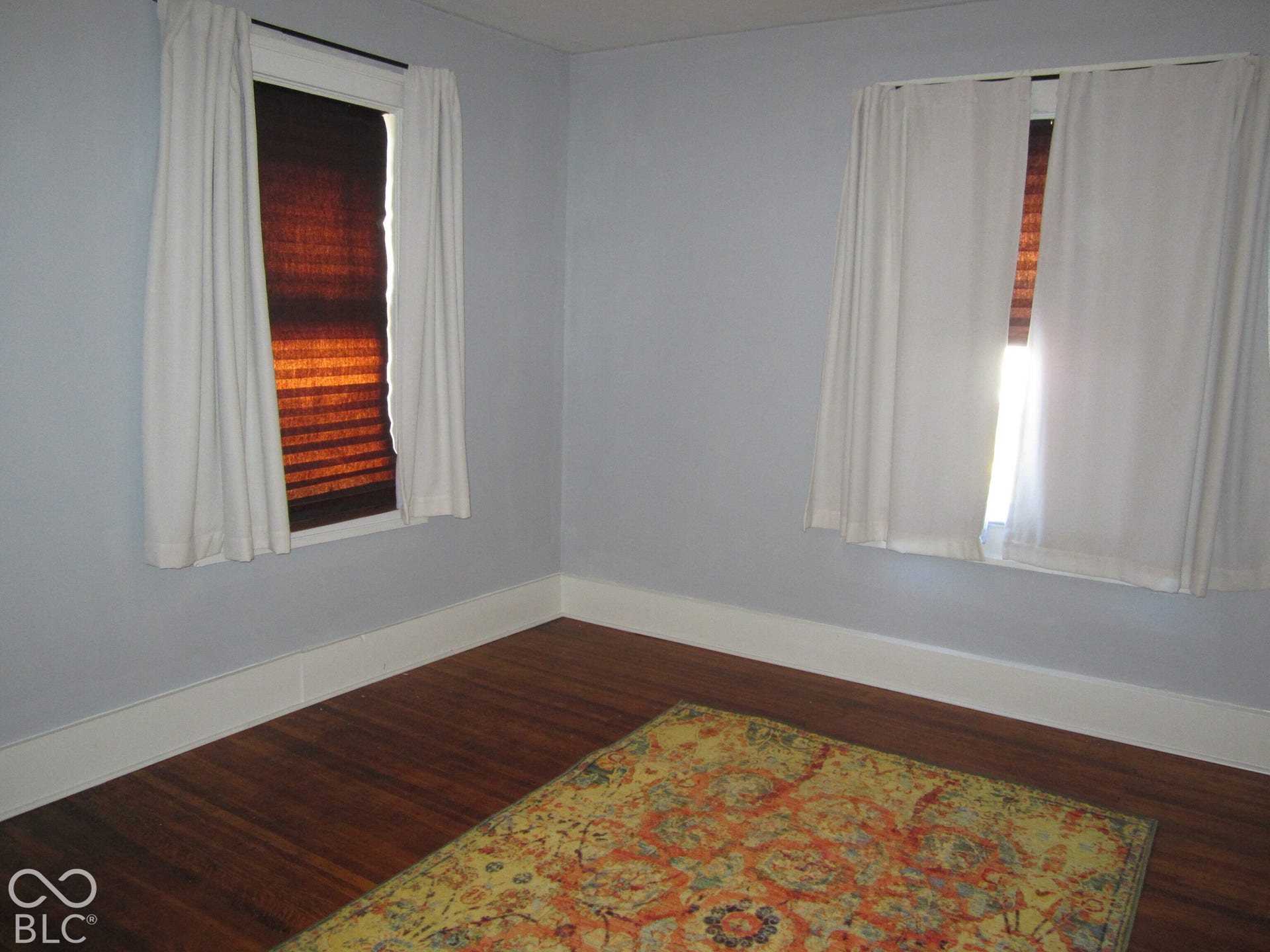 Room featuring wood-finish flooring and two windows with white trim