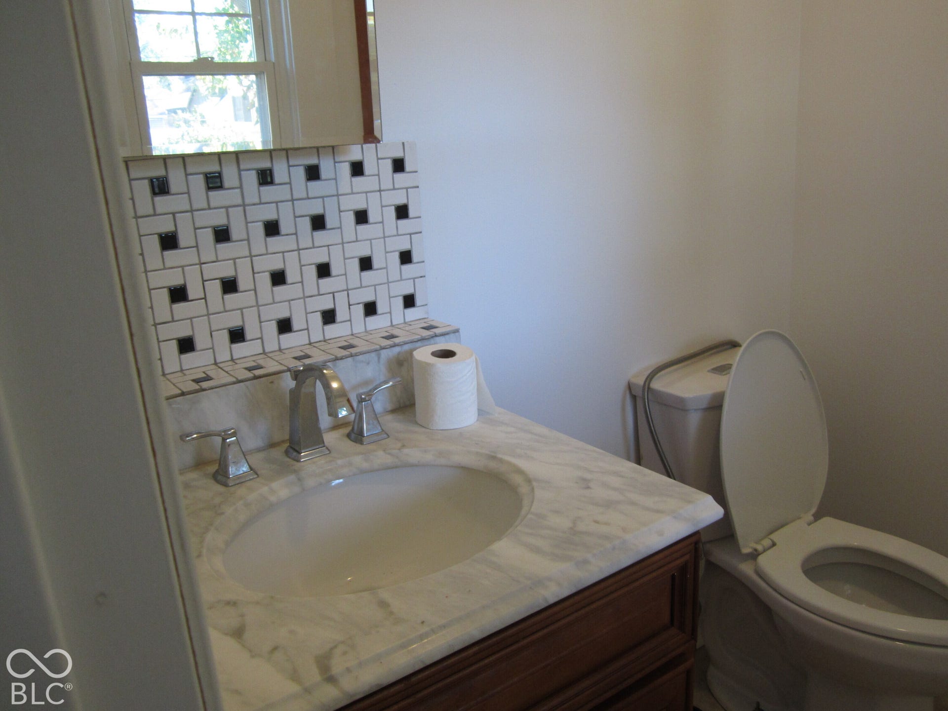 Vanity with natural stone countertop, integrated undermount sink, brushed nickel widespread faucet, and decorative geometric tile backsplash