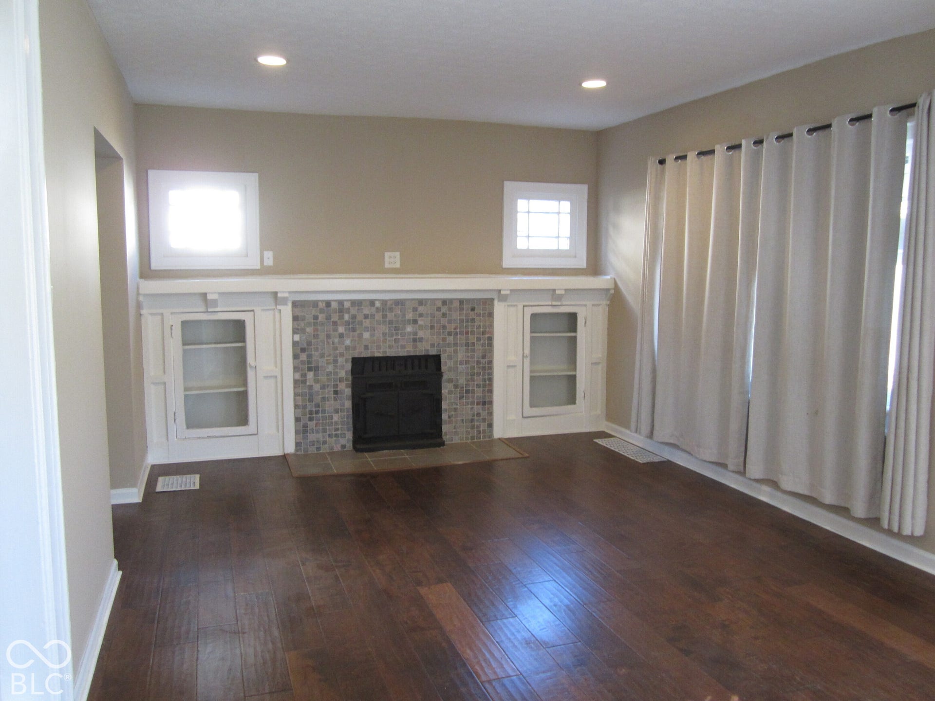 Fireplace featuring a mosaic tile surround, wood-finish flooring, built-in glass-front cabinetry, and recessed lighting