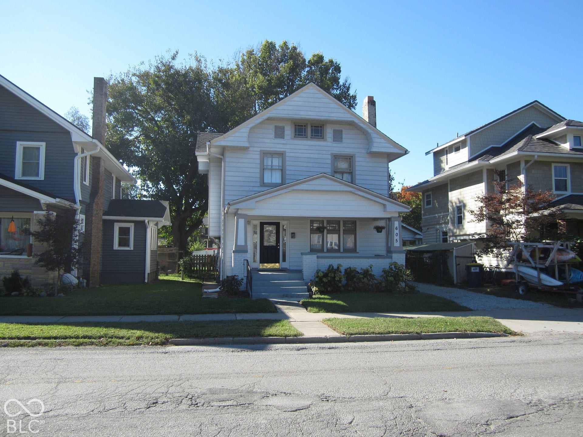 Two-story residence featuring horizontal siding, a covered front porch with tapered columns, gable roofline, and a private driveway