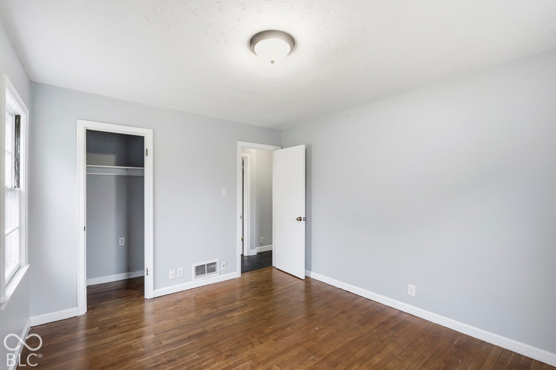 Interior room featuring wood-finish flooring, neutral wall paint, and a central flush-mount ceiling light