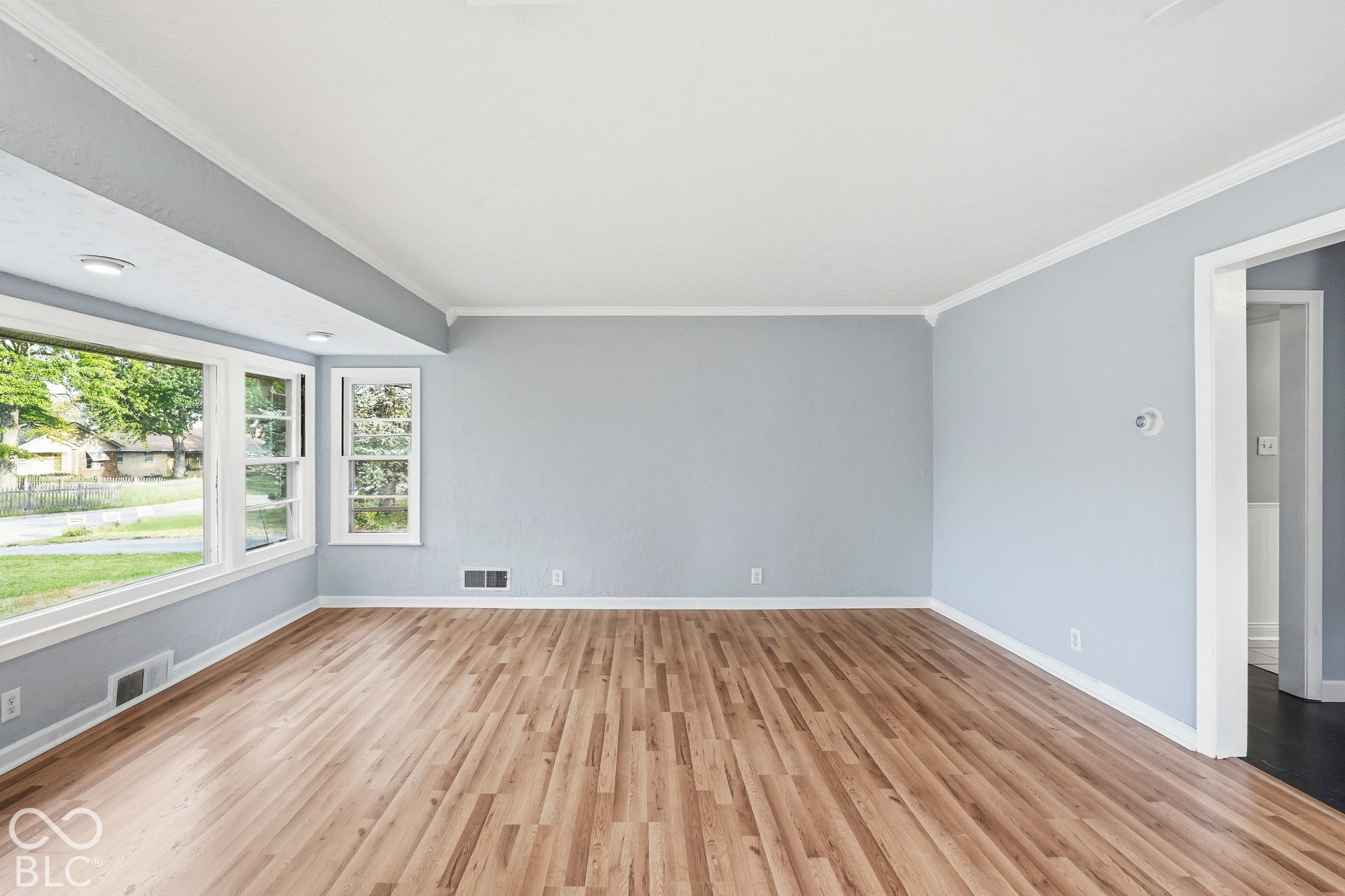 Living space featuring wood-finish flooring, recessed lighting, and a large bay window with white trim