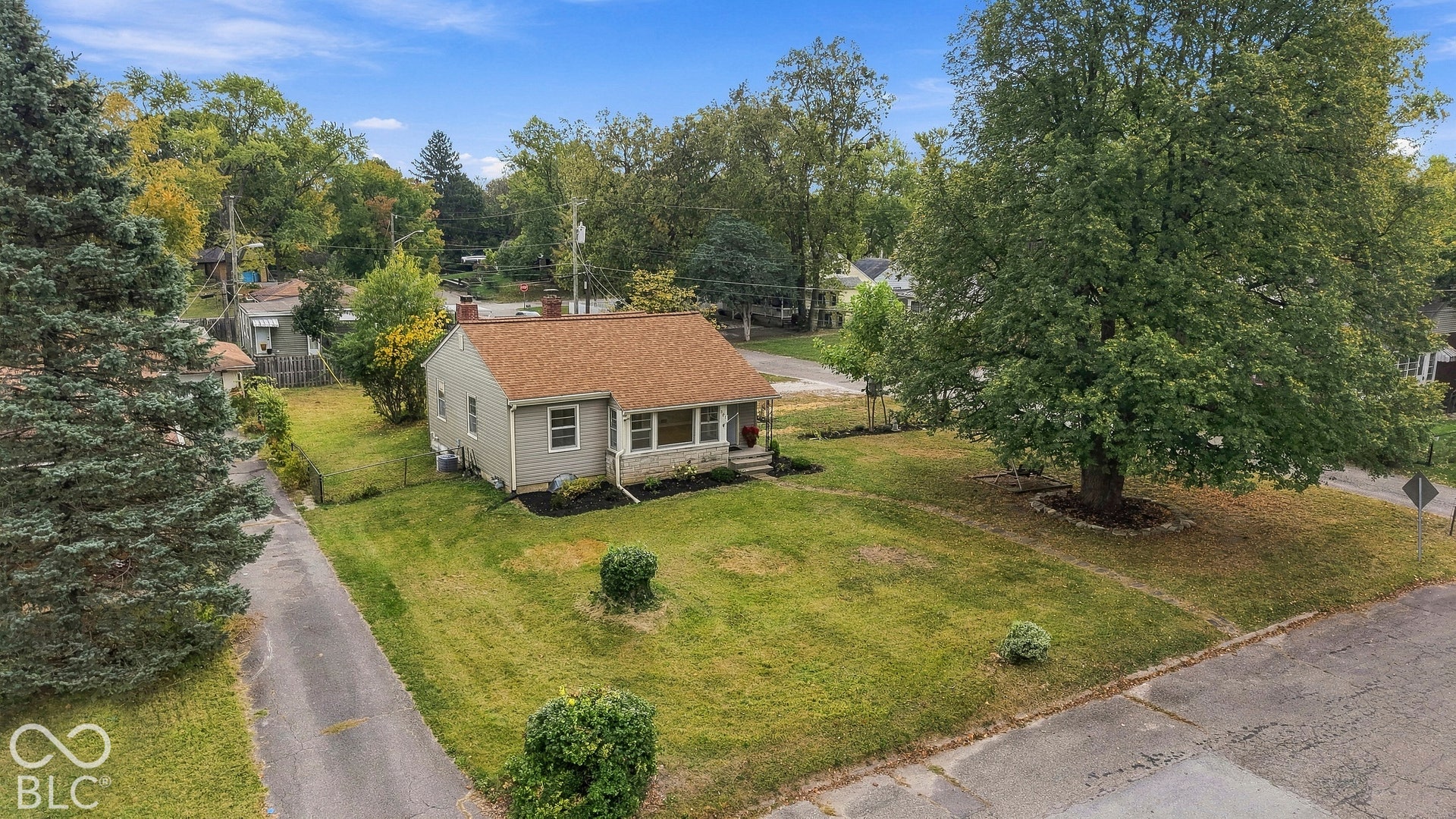 Exterior featuring light-toned siding, asphalt shingle roof, concrete driveway, and mature landscaping on a corner lot