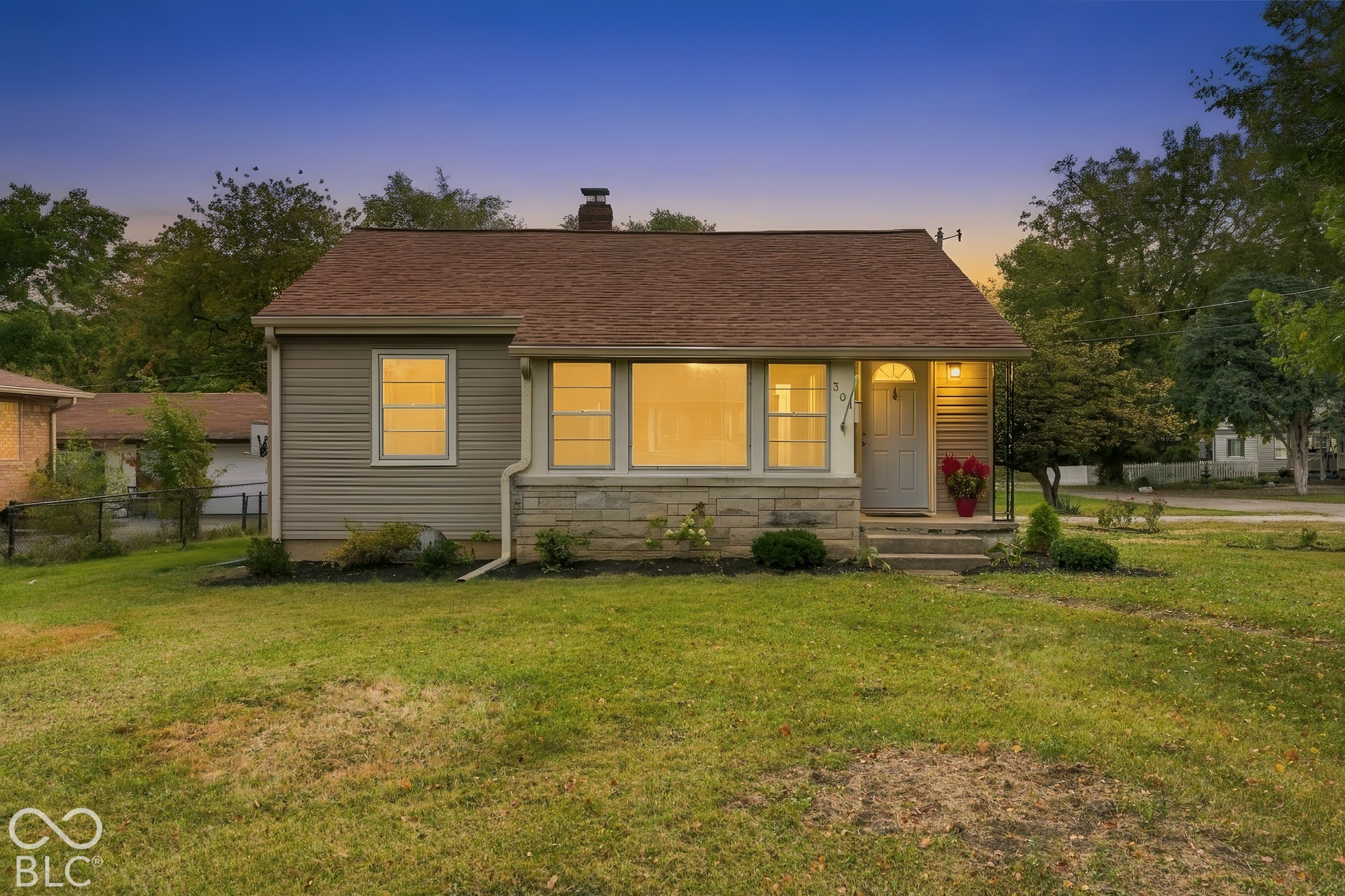 Exterior featuring a gable roof, stone masonry facade, horizontal siding, and an expansive front lawn