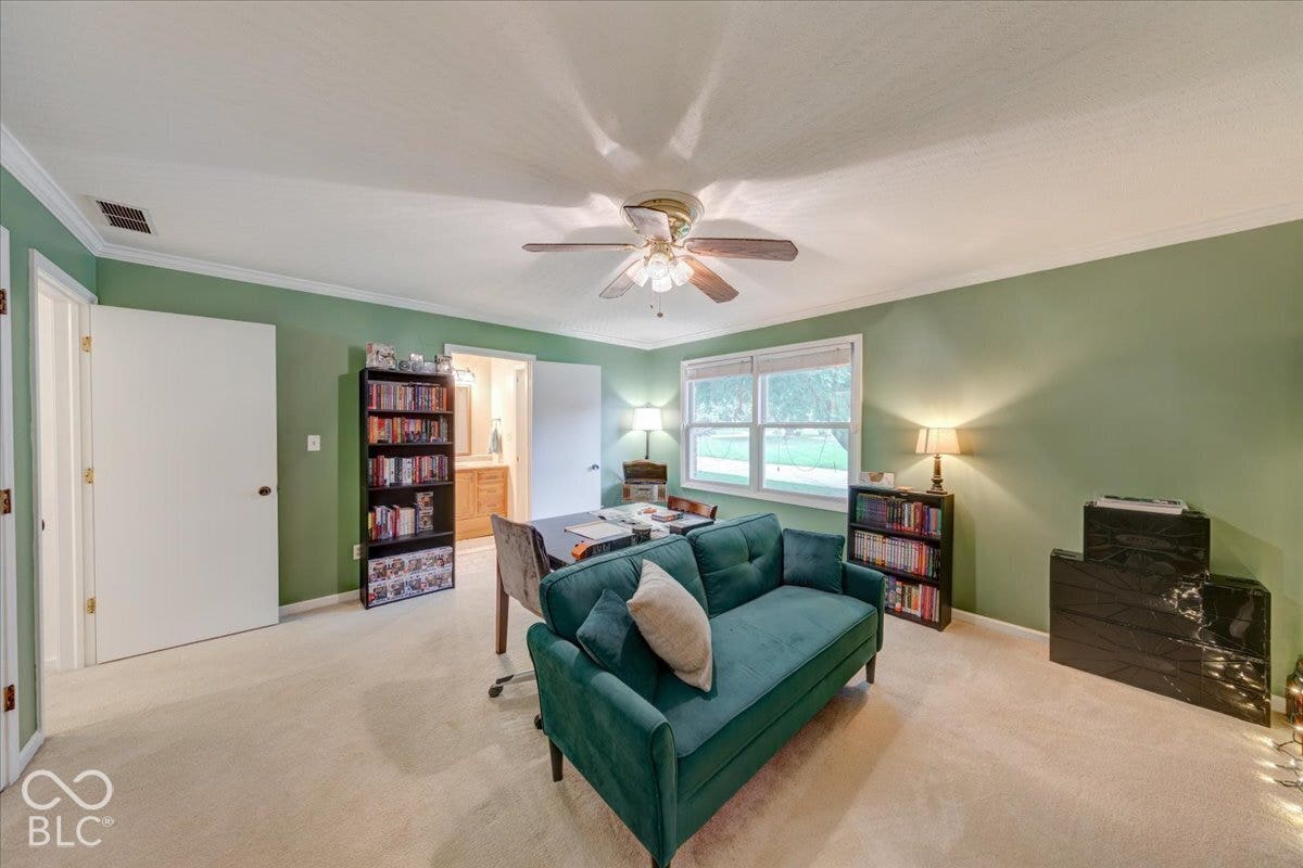Room featuring neutral carpeting, a ceiling fan with integrated light fixture, multi-pane window, and interior door leading to a separate space