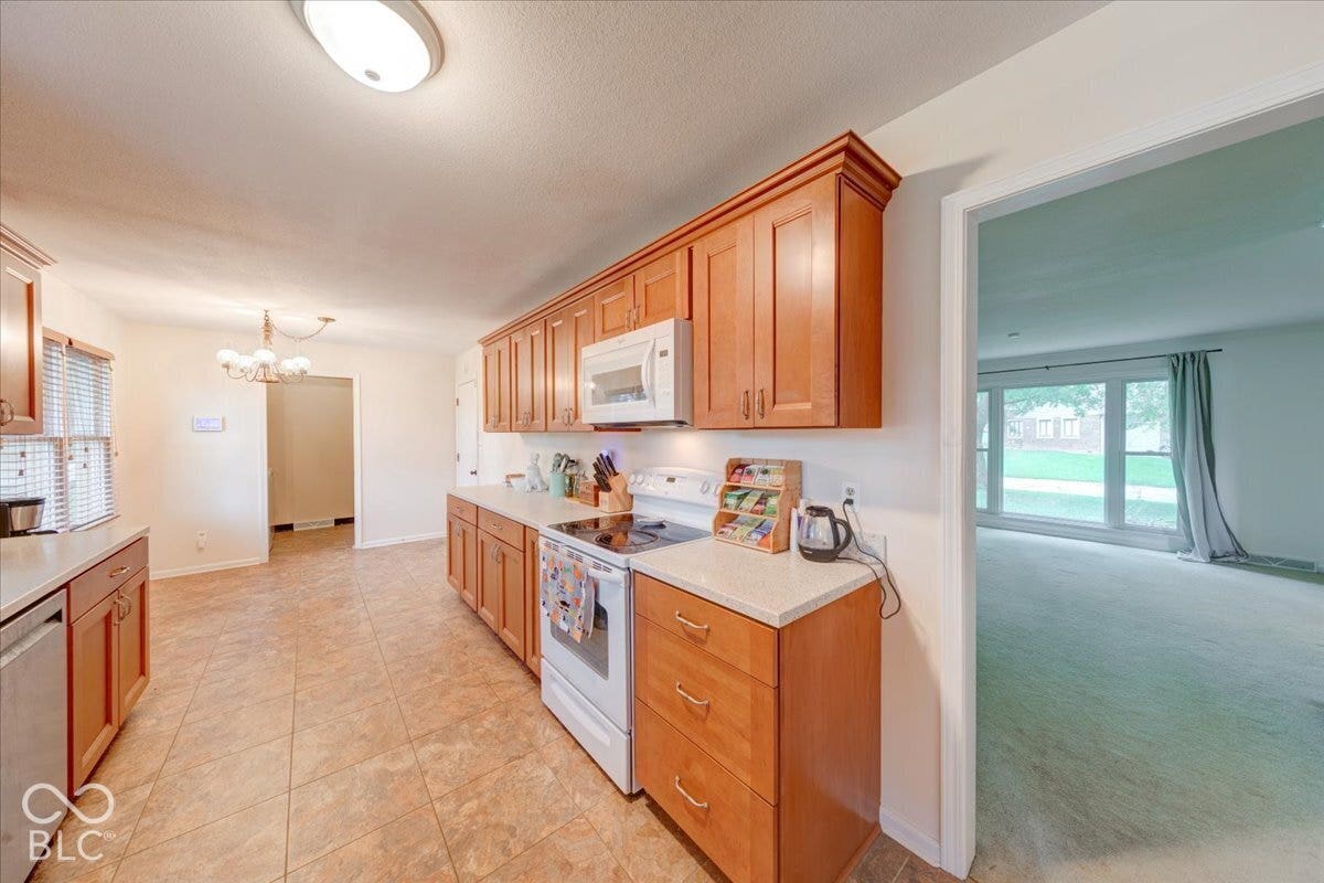 Kitchen featuring wood cabinetry, stone-finish countertops, ceramic tile flooring, and built-in appliances