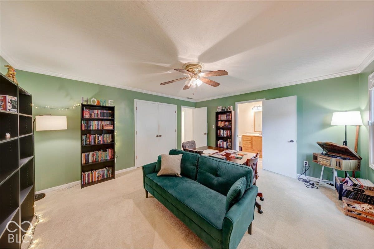 Spacious room featuring neutral carpeting, a central ceiling fan with integrated light fixture, dual-door closet, and crown molding