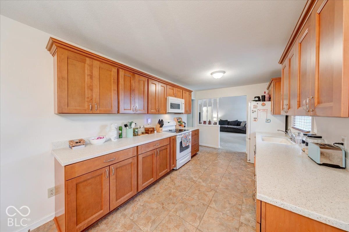 Kitchen featuring wood cabinetry, stone-finish countertops, ceramic tile flooring, and a built-in microwave