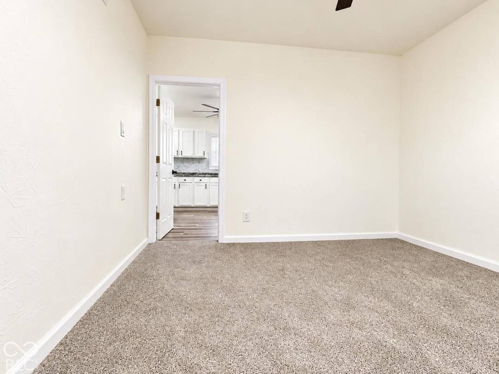 Neutral-toned wall-to-wall carpeting, ceiling fan with integrated lighting, and white door trim