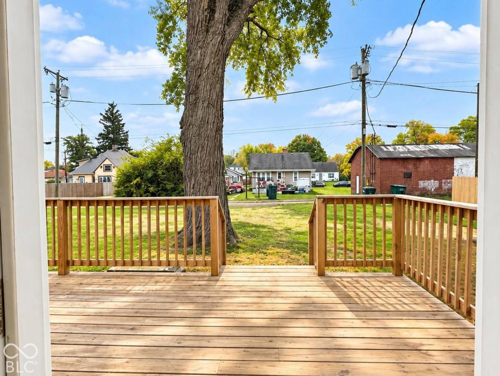 Elevated wooden deck featuring vertical baluster railings and a mature shade tree