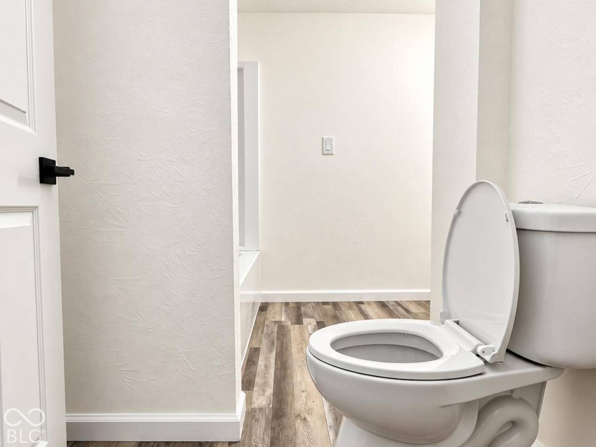 Bathroom featuring wood-finish flooring, a two-piece toilet, and a matte black door lever