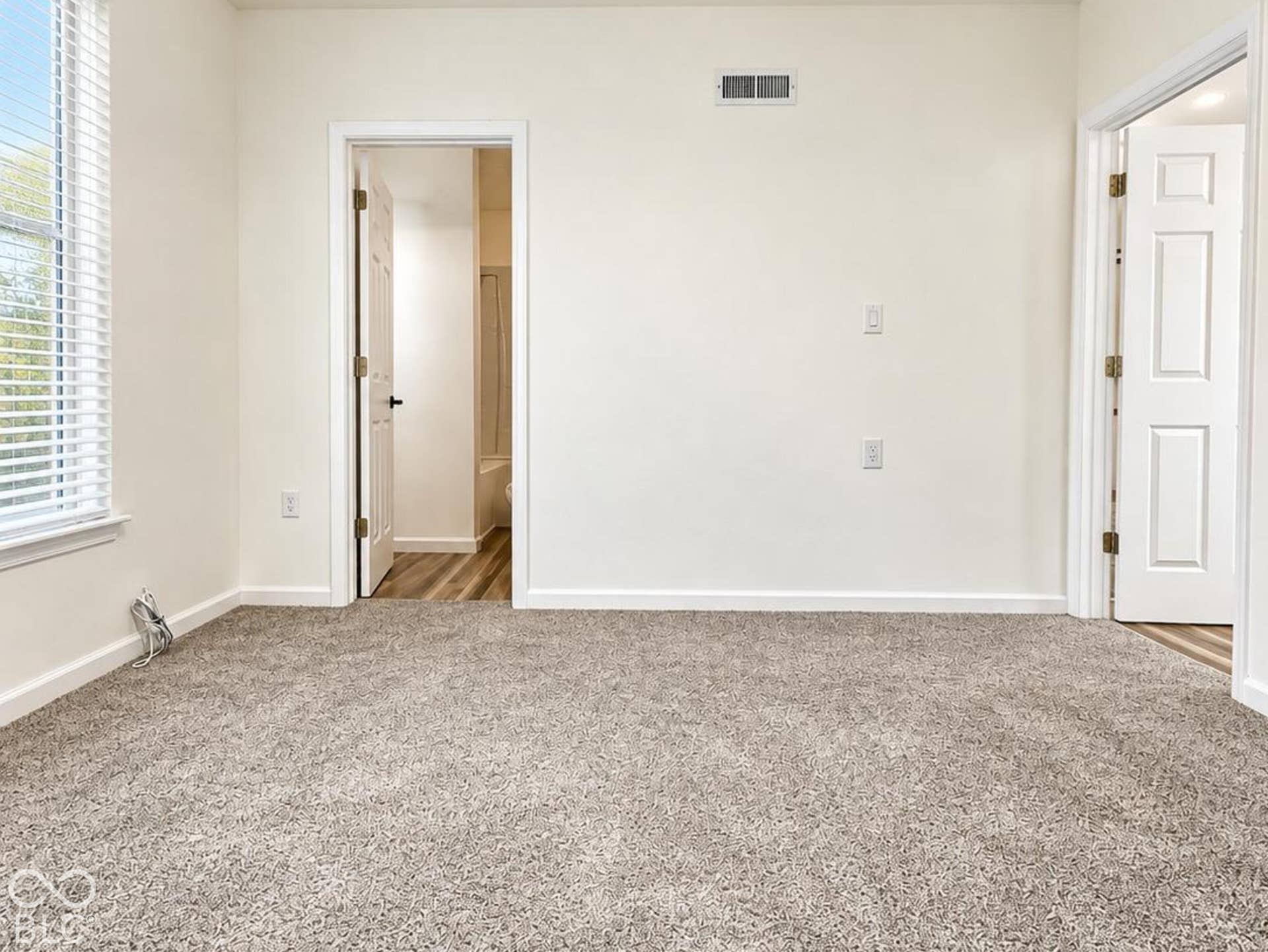 Neutral-toned carpeting, matte black ceiling fan with integrated lighting, multi-pane window with horizontal blinds, and paneled interior doors