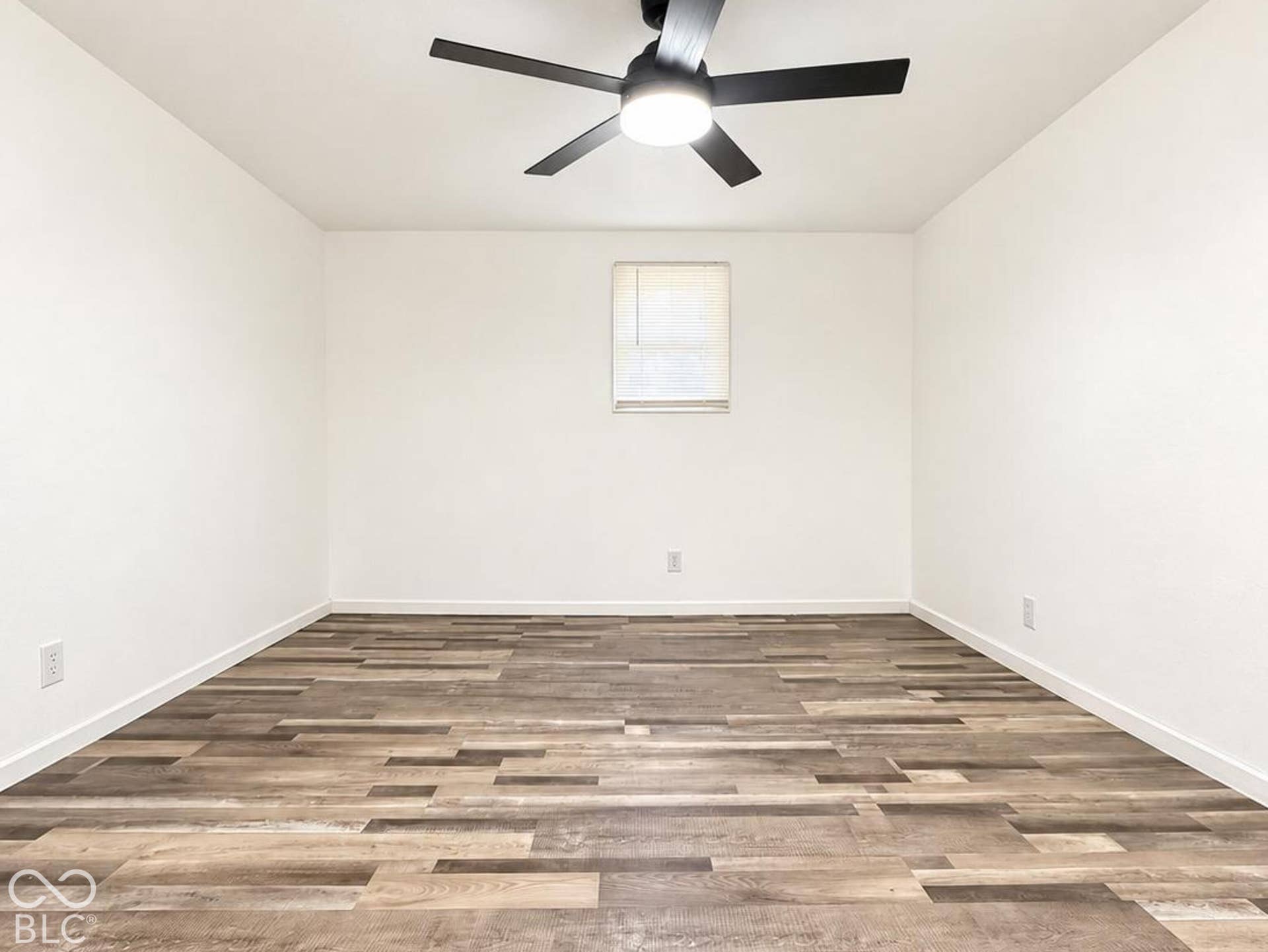 Interior space featuring wood-finish flooring, white walls, and a ceiling-mounted fan with integrated light fixture