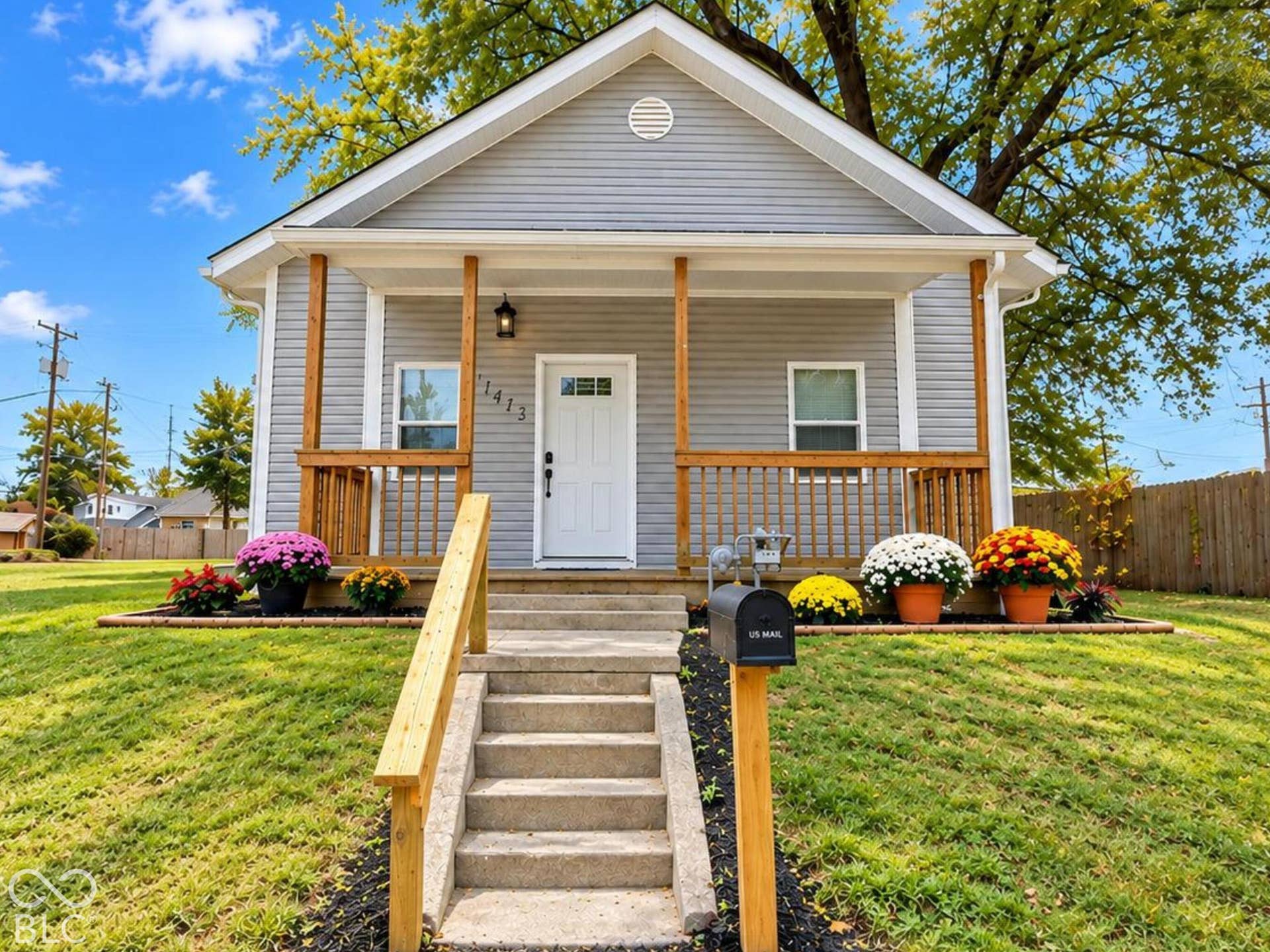 Craftsman-style exterior featuring grey horizontal siding, a covered front porch with wood railings, concrete front steps, and a landscaped yard