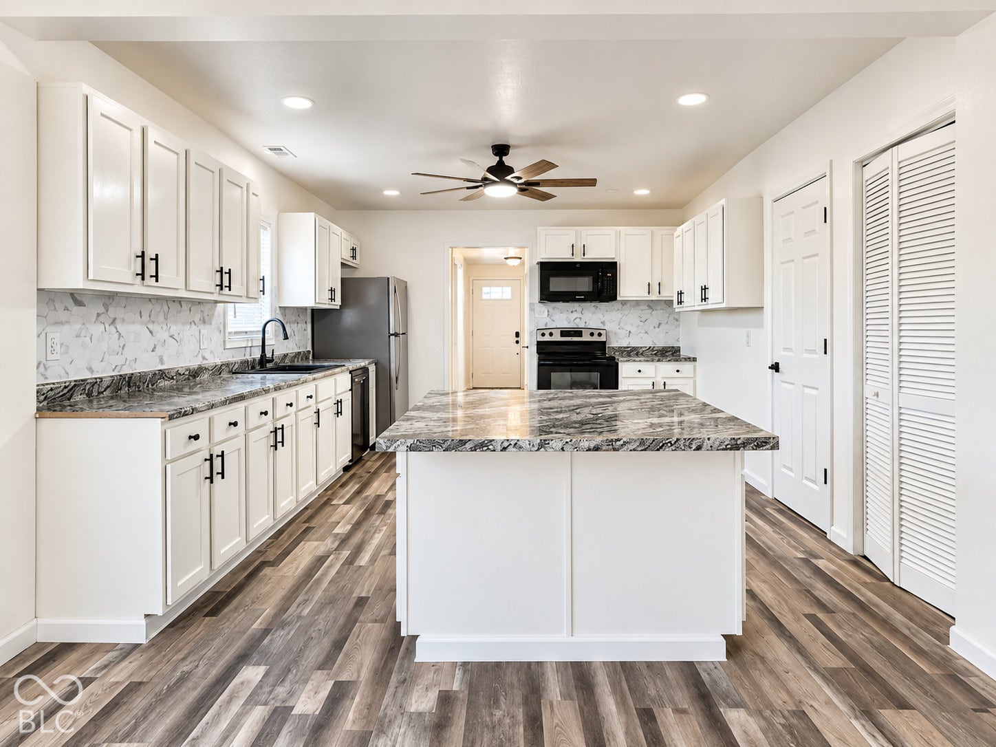 Kitchen featuring white cabinetry, stone-patterned countertops, wood-finish flooring, a central island, and matte black hardware
