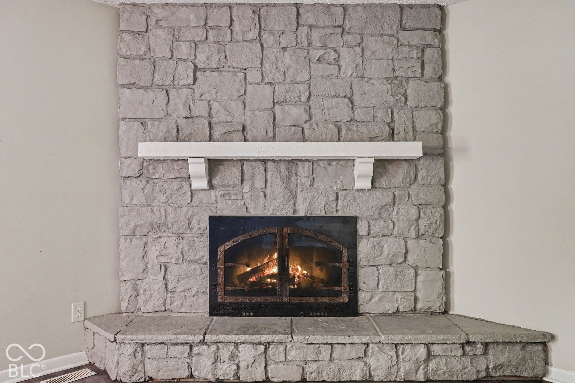 Floor-to-ceiling stone fireplace surround with a white mantle and stone hearth