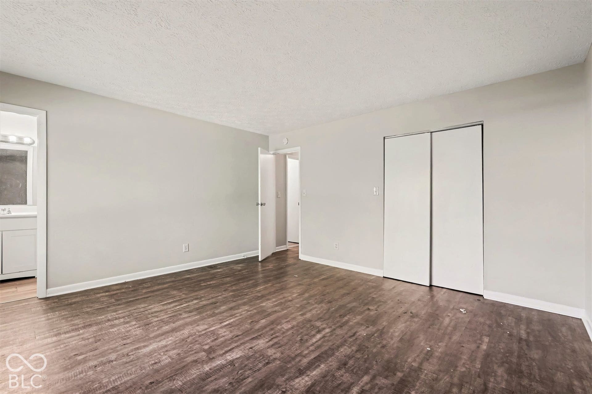 Room interior featuring wood-finish flooring, neutral wall paint, and a built-in closet with sliding doors