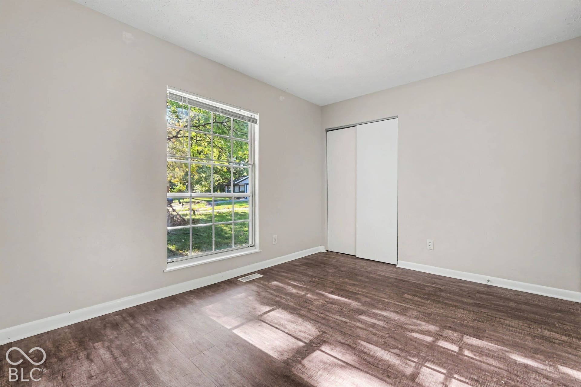 Neutral-toned interior featuring wood-finish flooring, a large grid-pattern window, and sliding-panel closet doors