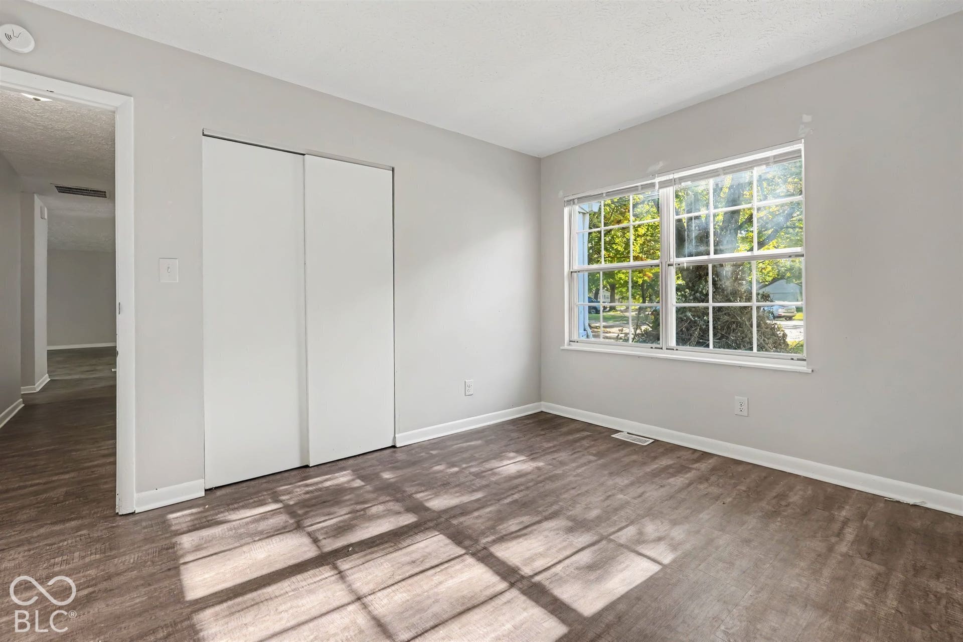 Neutral interior featuring wood-finish flooring, sliding closet doors, and a double-pane window with a grid pattern